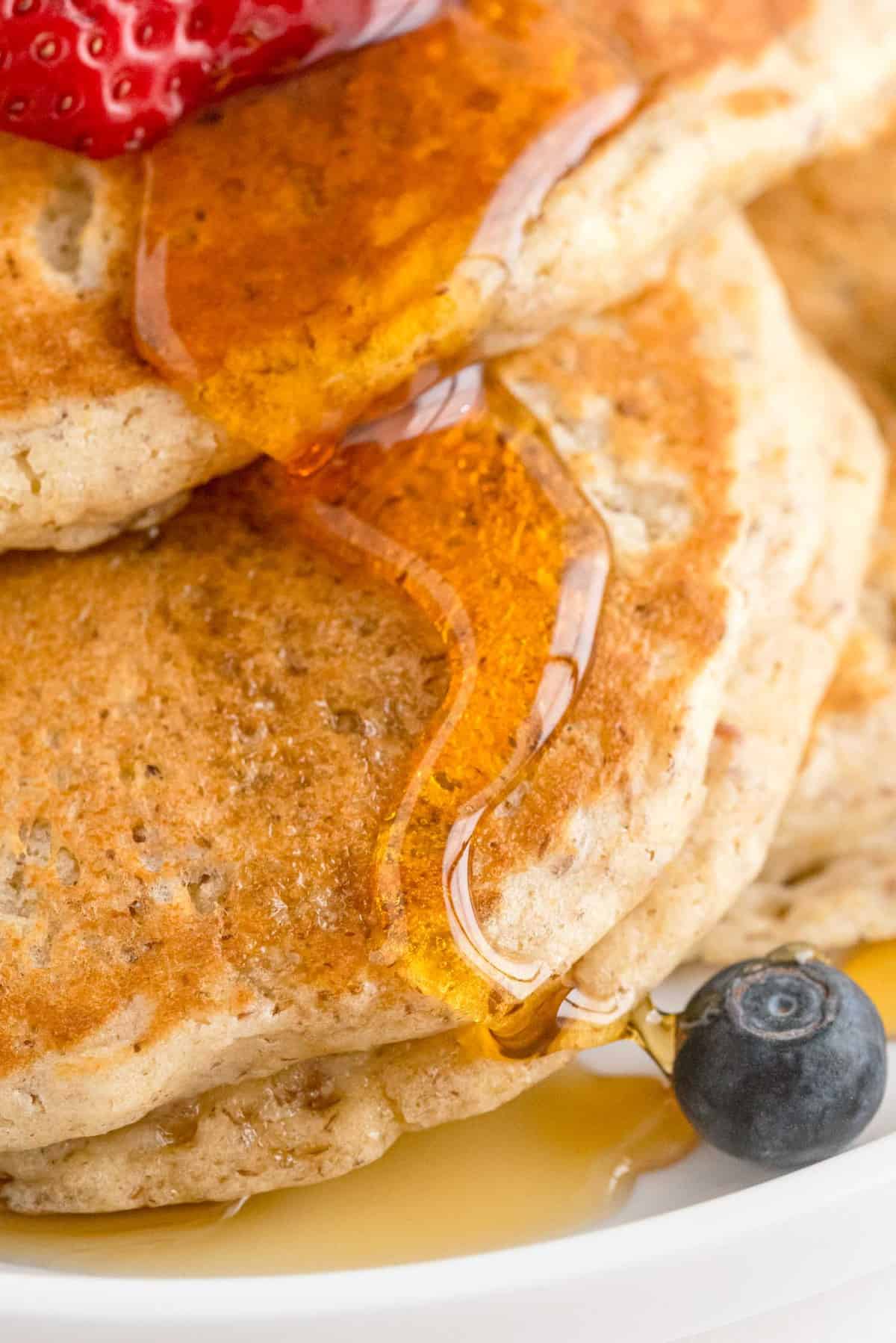 Close up of syrup dripping down pancakes.