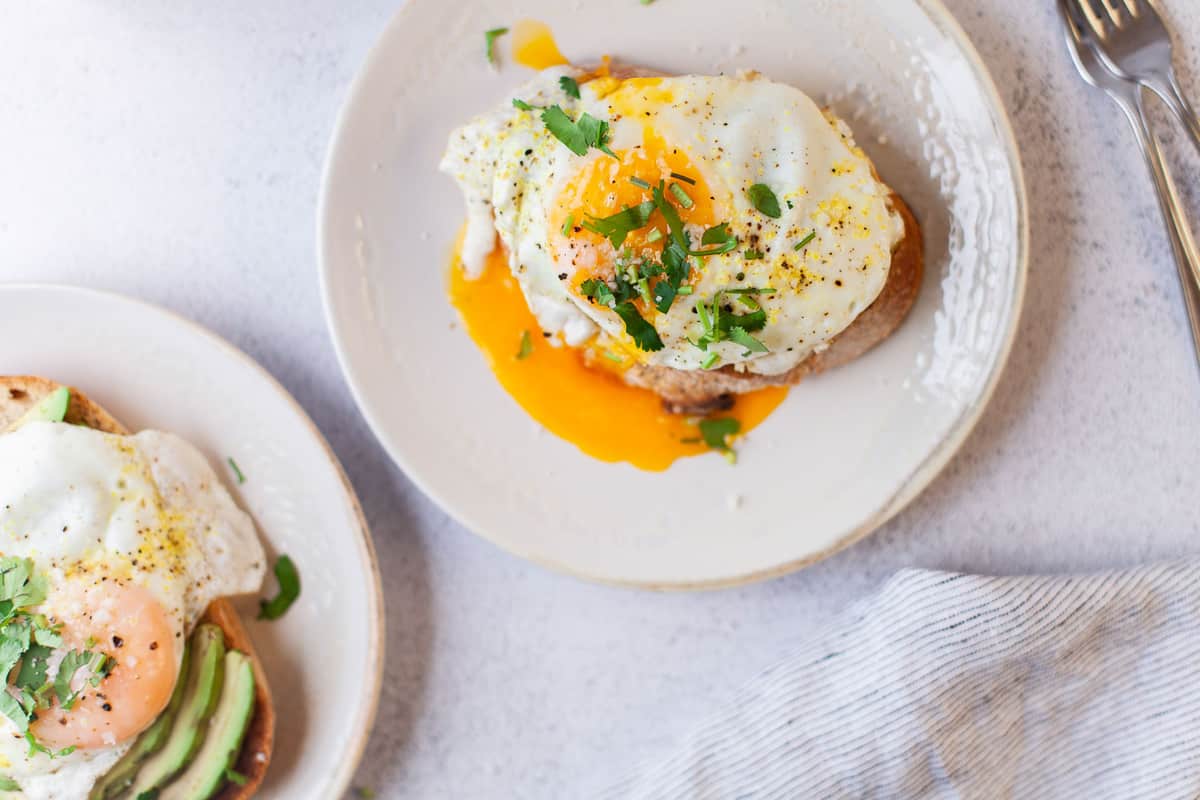 Overhead view of a runny egg on top of avocado toast.