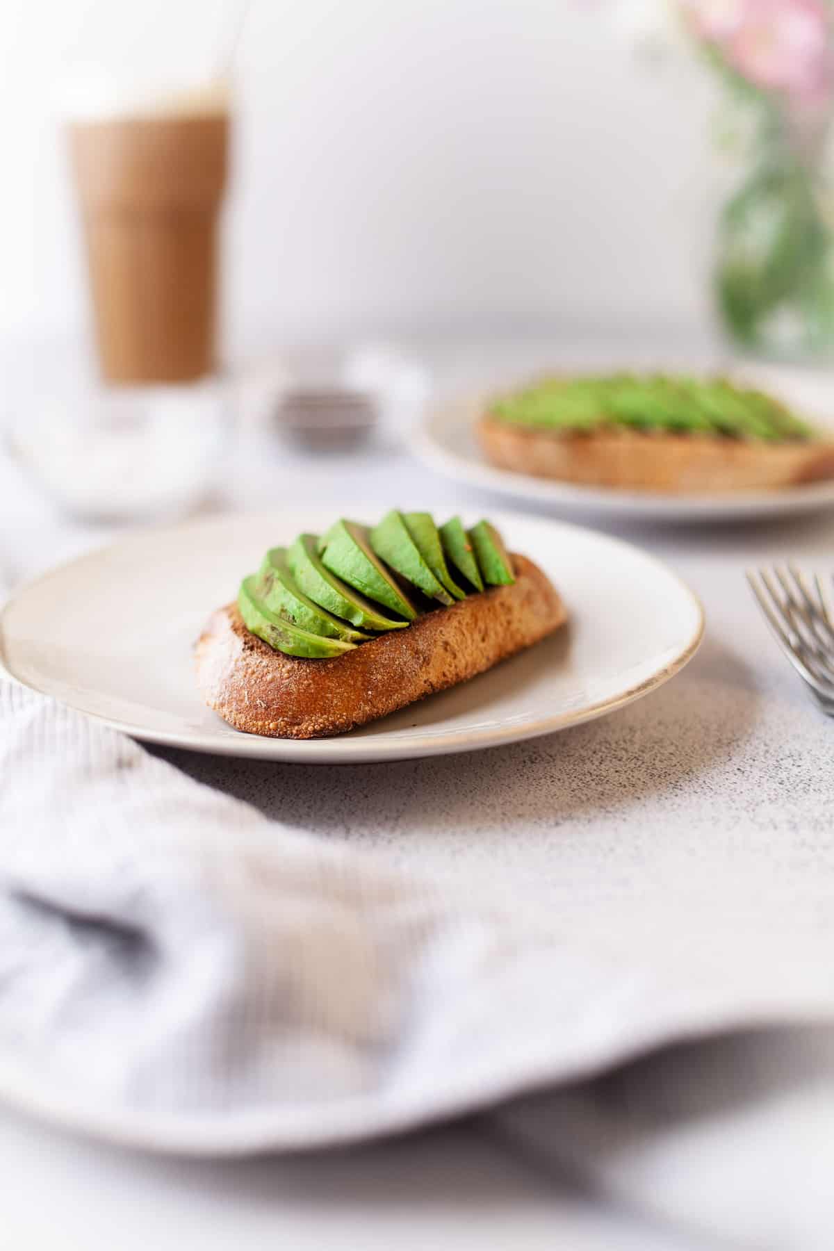 Slices of avocado on top of toast on a white plate.