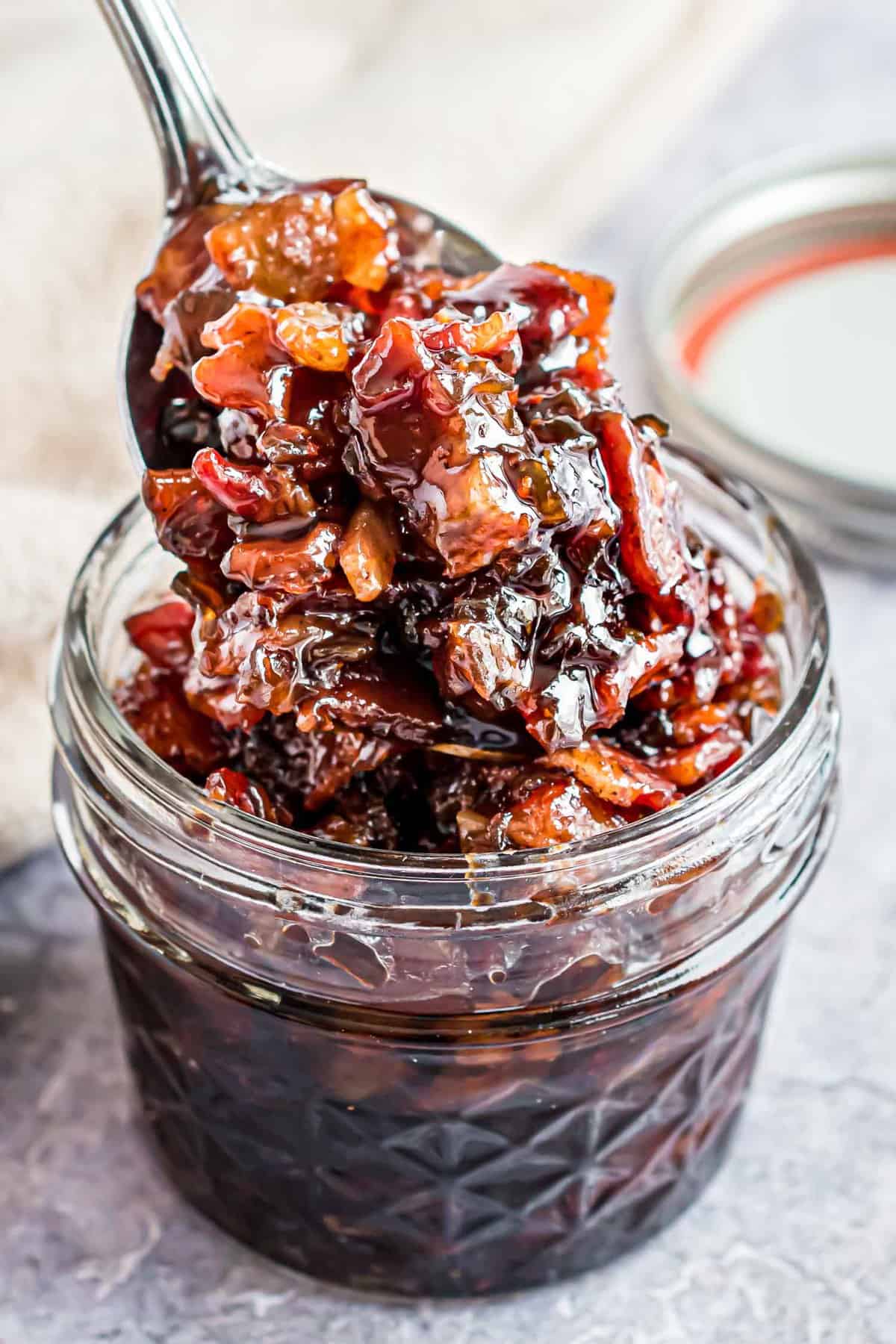 Close up of bacon jam in a jar and on a spoon.