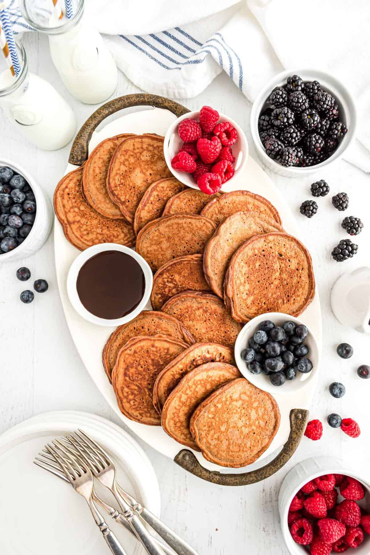 Chocolate pancakes arranged on a platter with fresh berries.