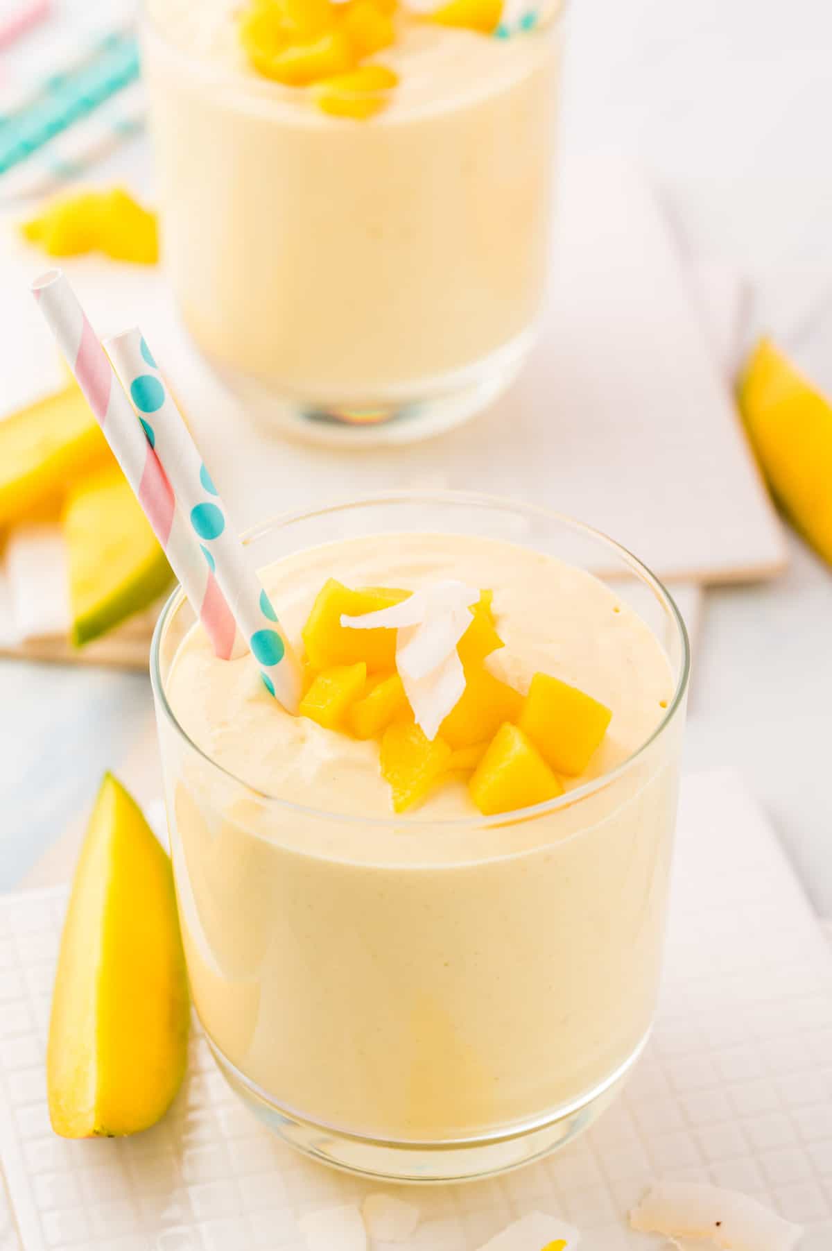 Smoothie topped with fresh mango and shredded coconut. Another in the background.