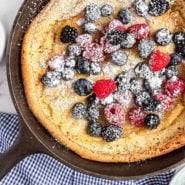 A dutch baby pancake topped with fruit and powdered sugar.