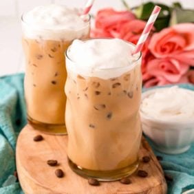 Two iced vanilla lattes topped with whipped cream.
