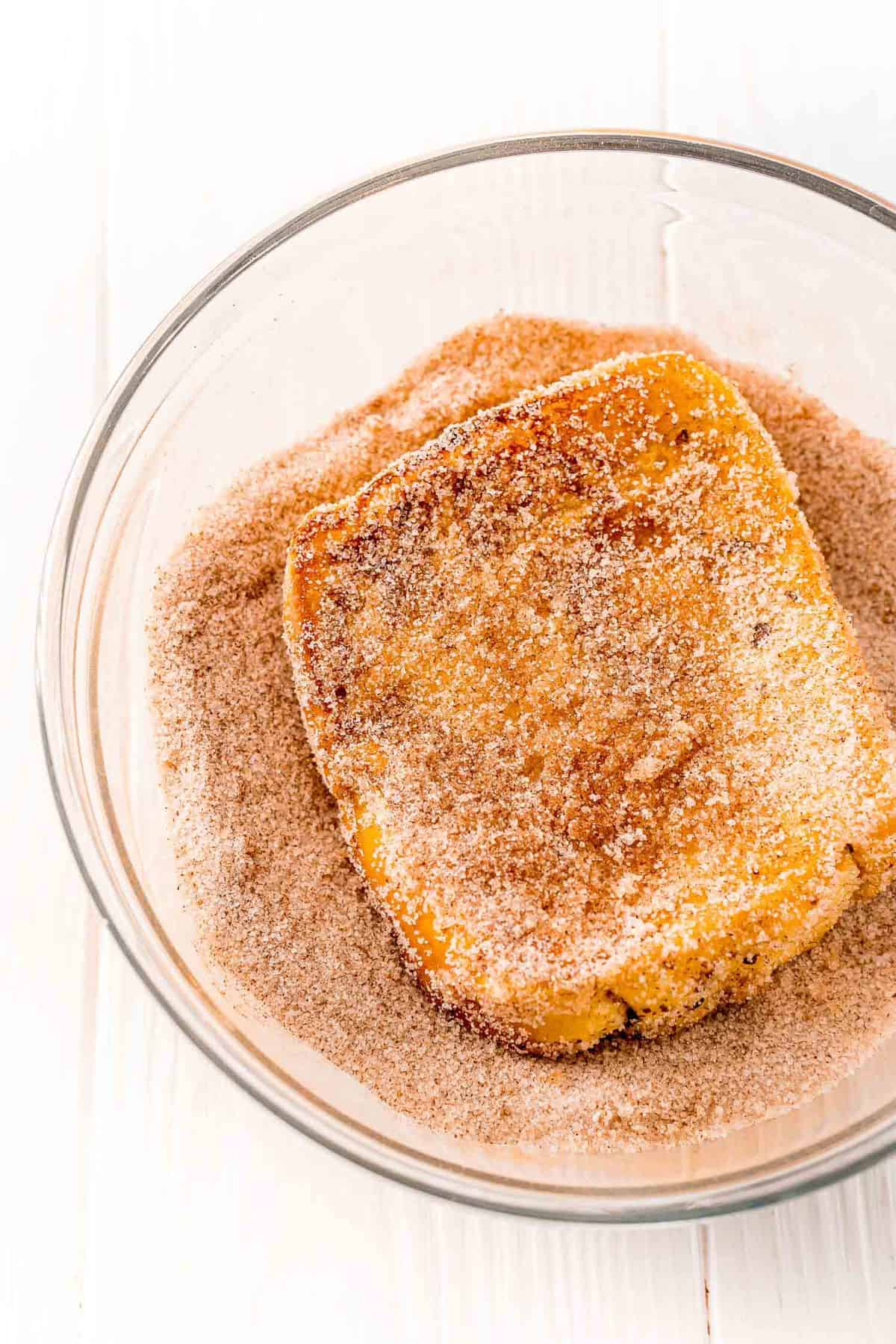 French toast being dipped in cinnamon sugar.