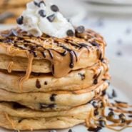 Stack of pancakes drizzled with peanut butter and chocolate.