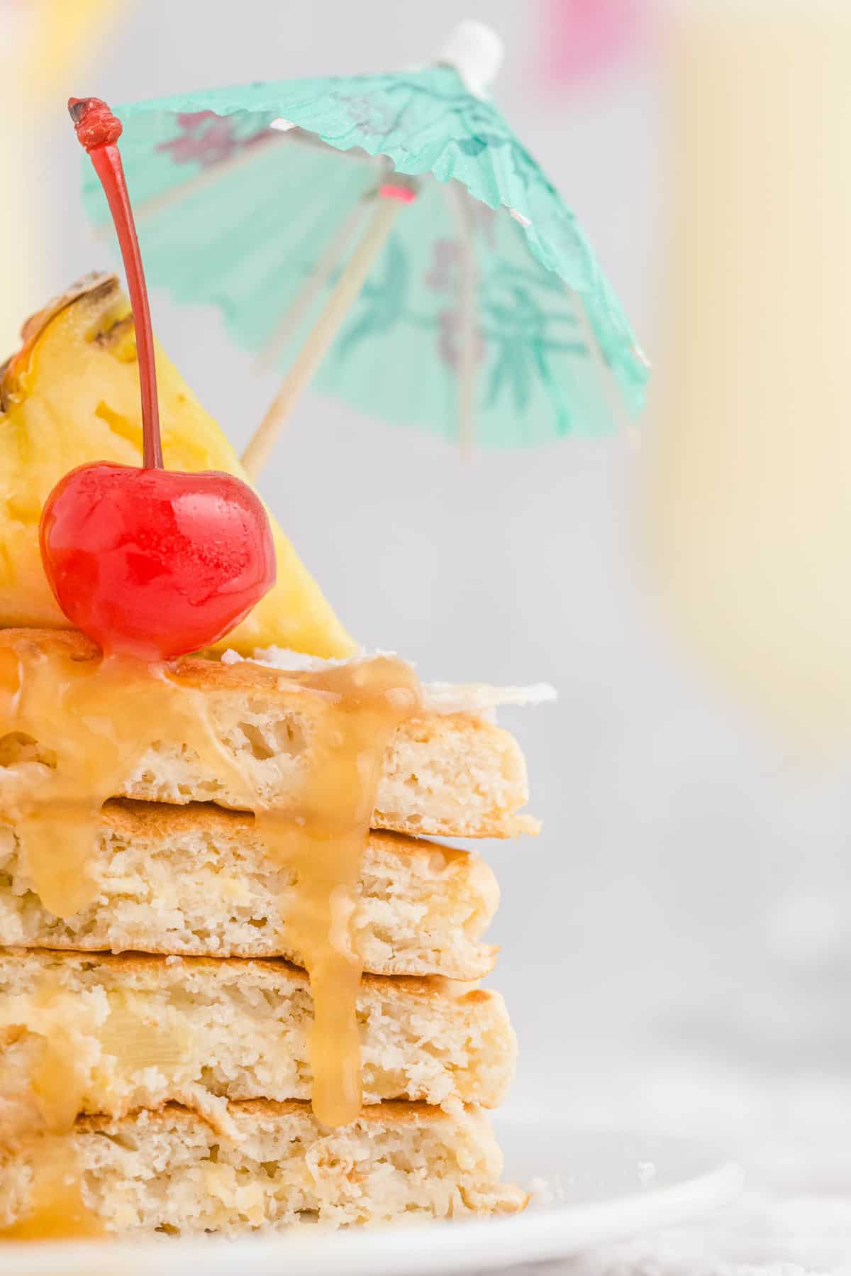Close up of caramel sauce dropping down cut pancakes with a tropical vibe.