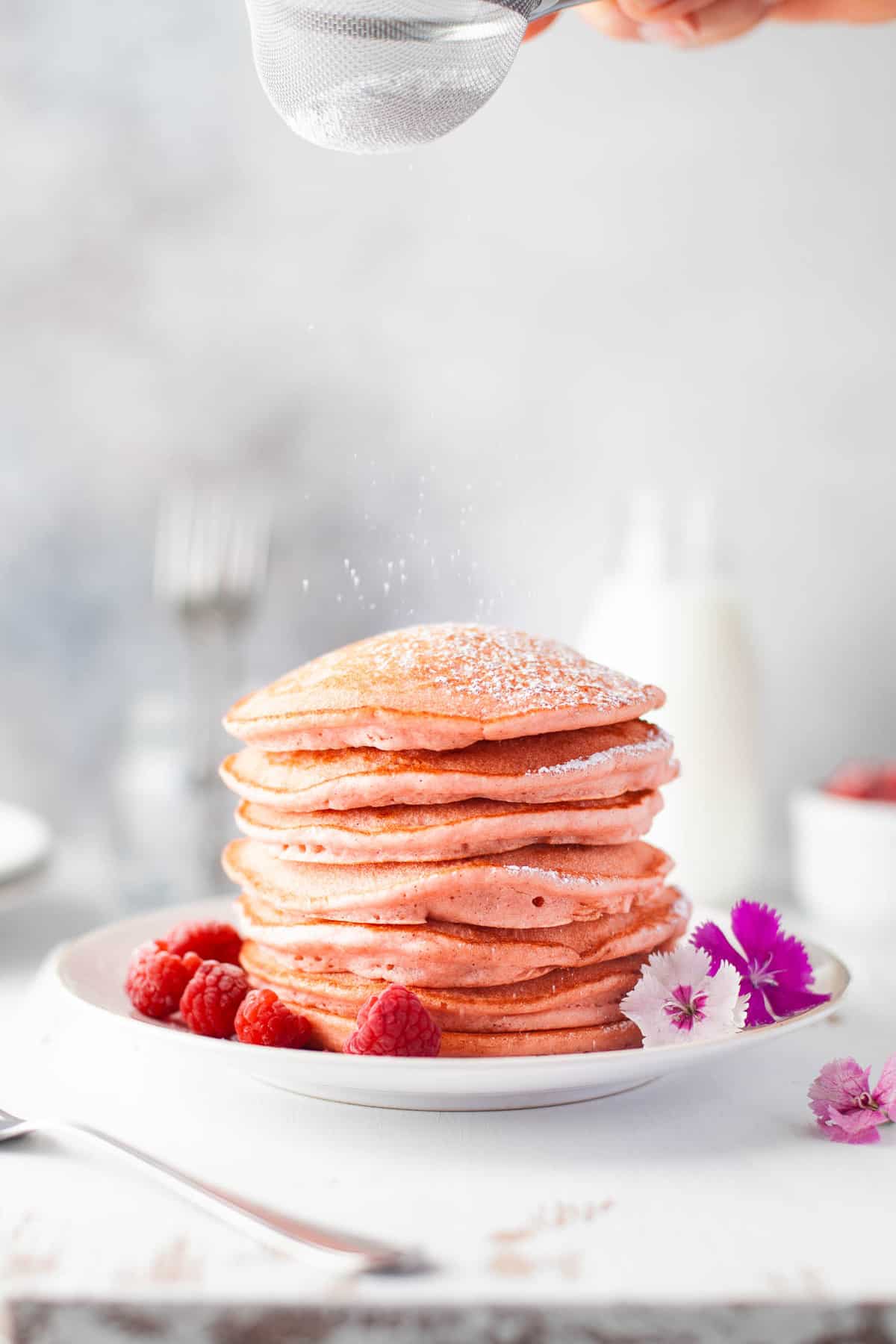 Pancakes being sprinkled with powdered sugar.