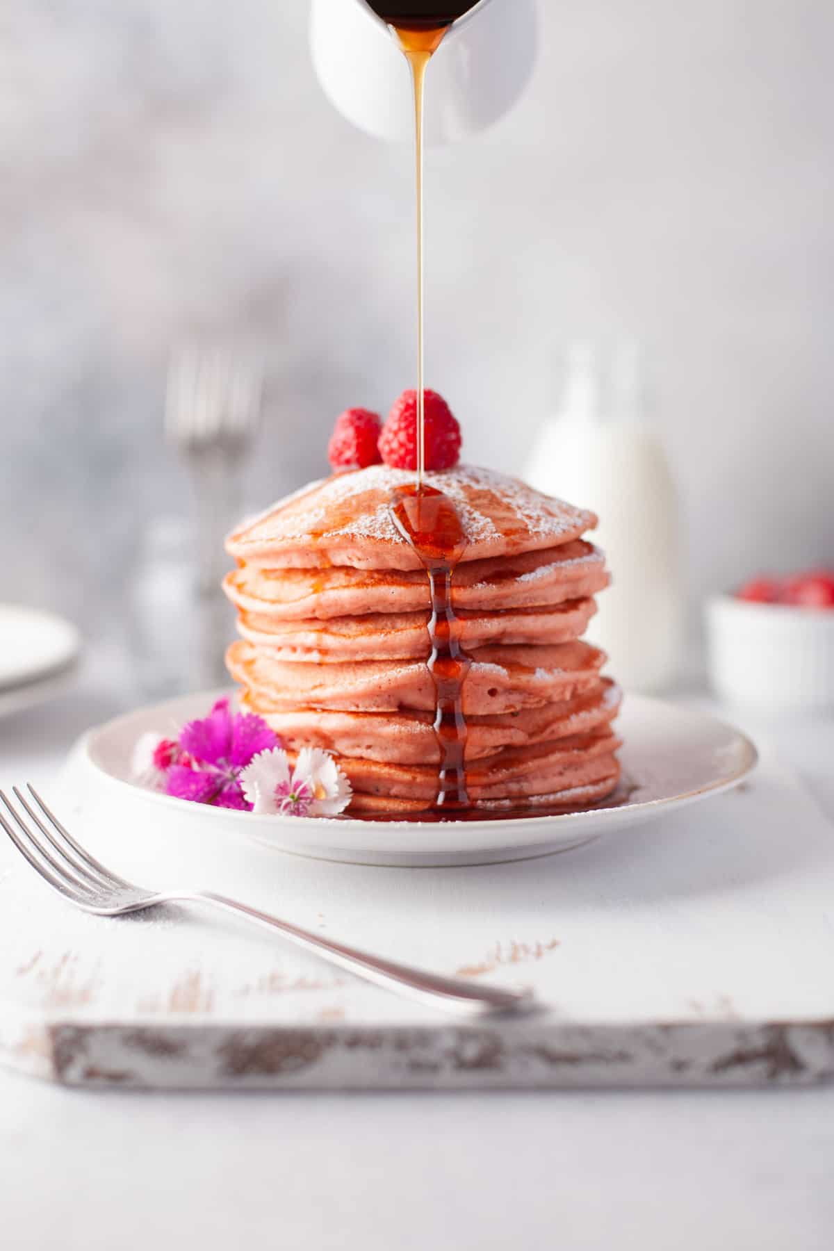 Syrup being poured on a stack of beet pancakes.