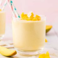 Mango smoothie in short glass, topped with coconut and mango.