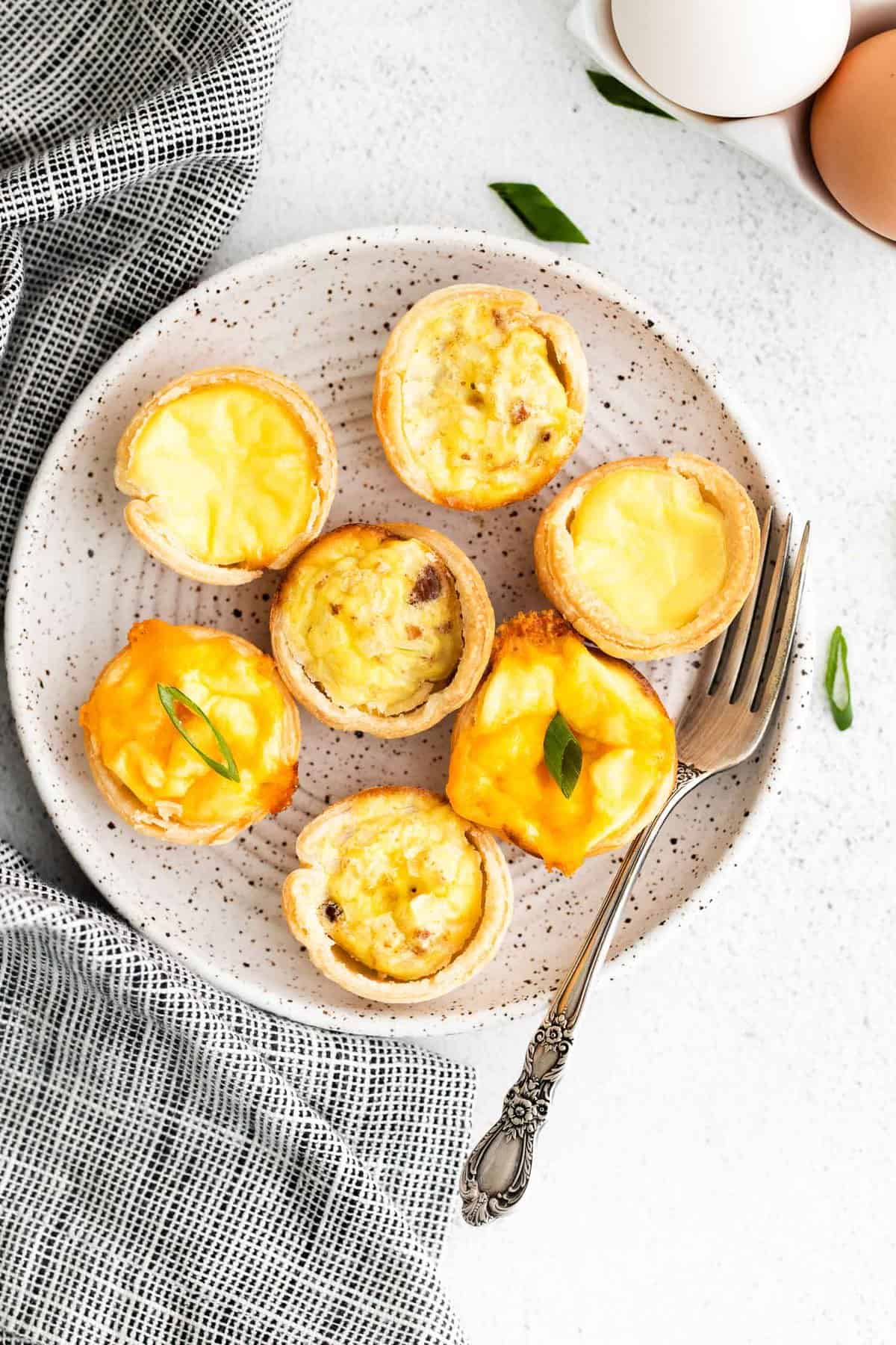 3 varieties of mini quiches on a small round plate.