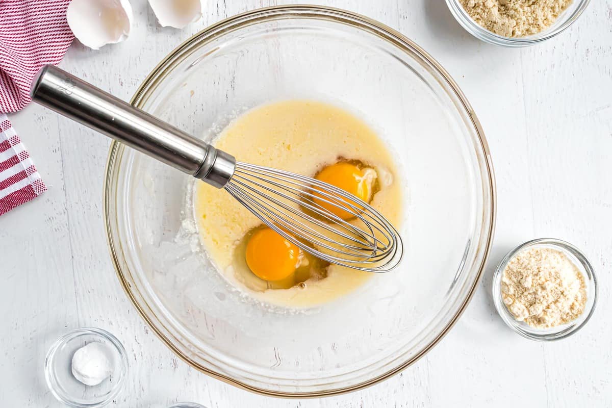 Eggs, milk, and butter in a glass mixing bowl.
