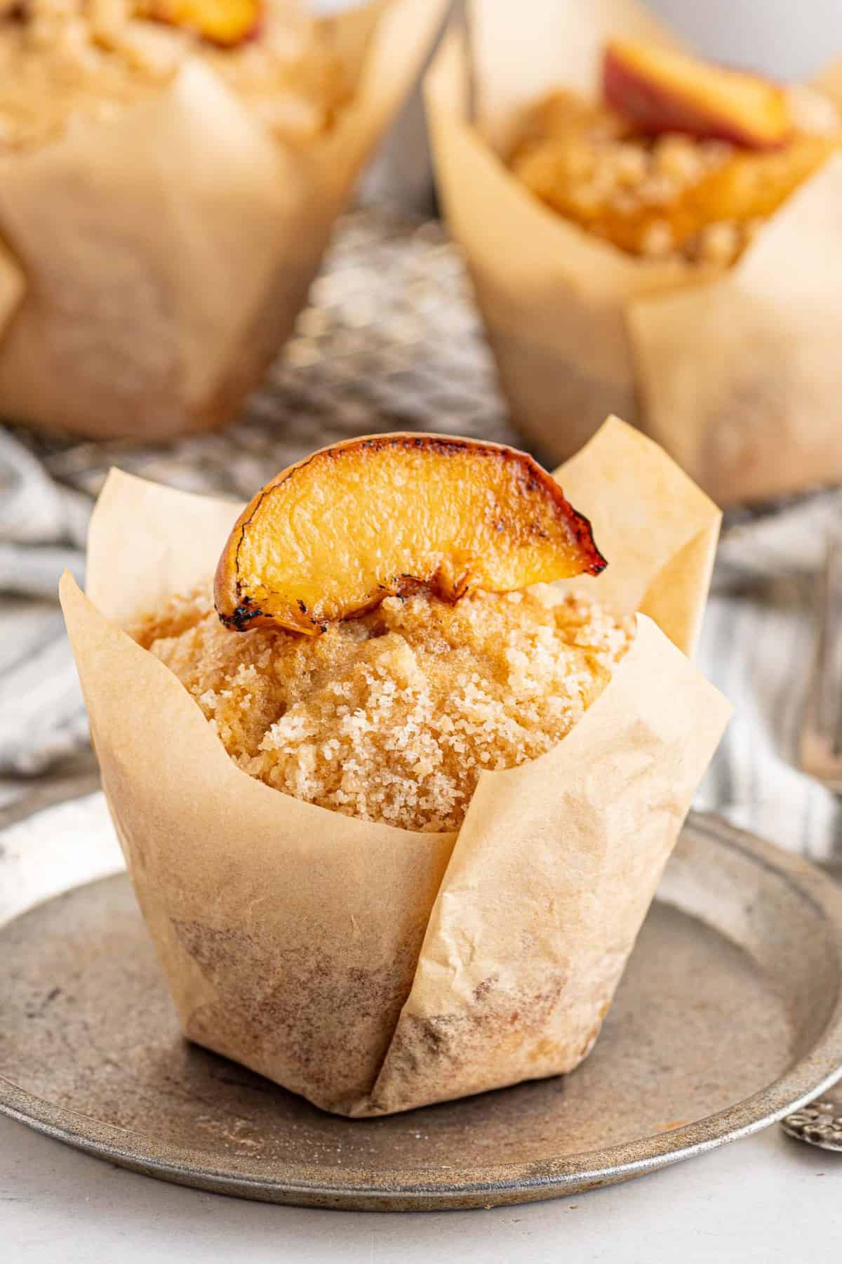 Peach streusel muffin with parchment paper lining.