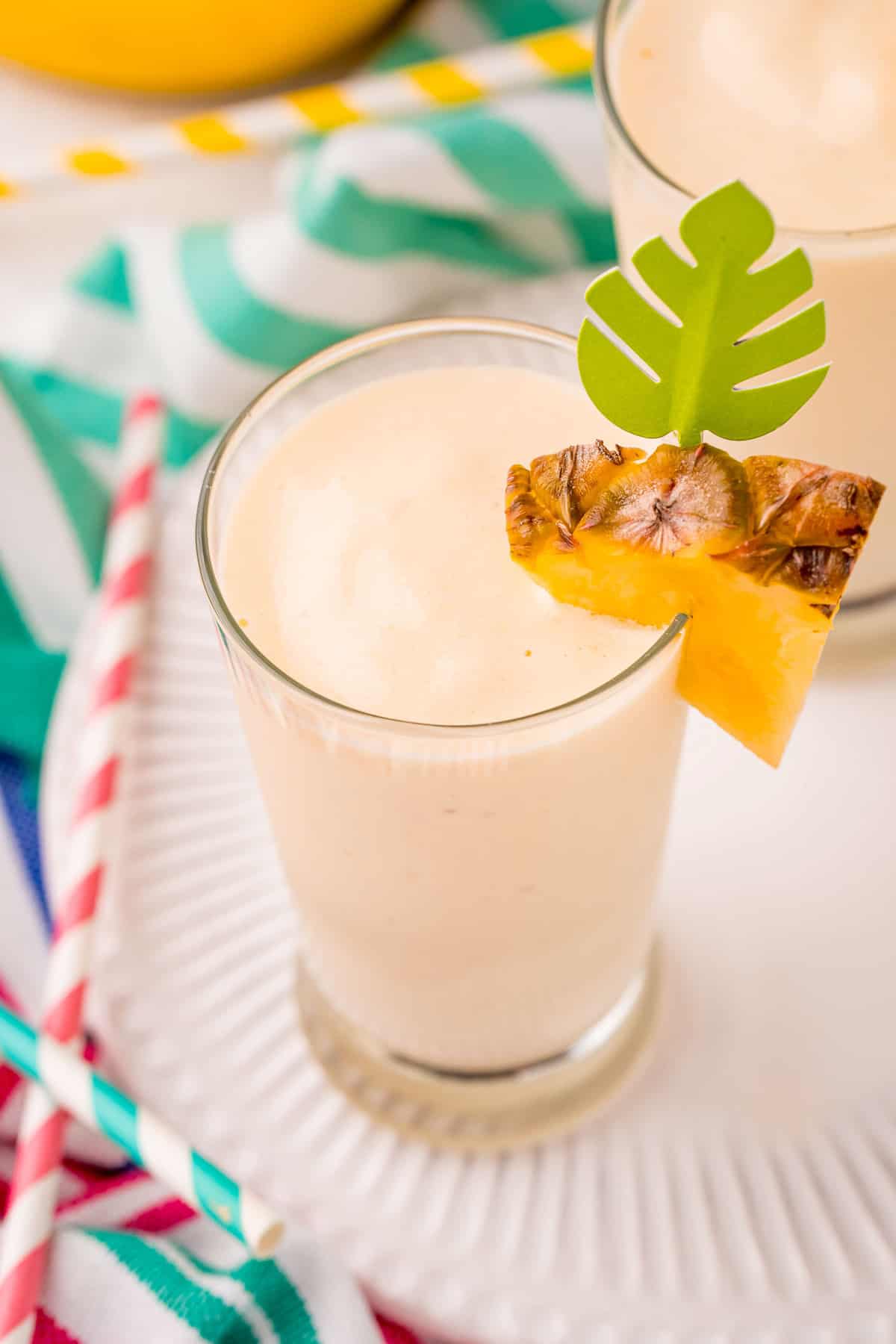 Overhead view of pineapple smoothie garnished with fresh pineapple wedge.