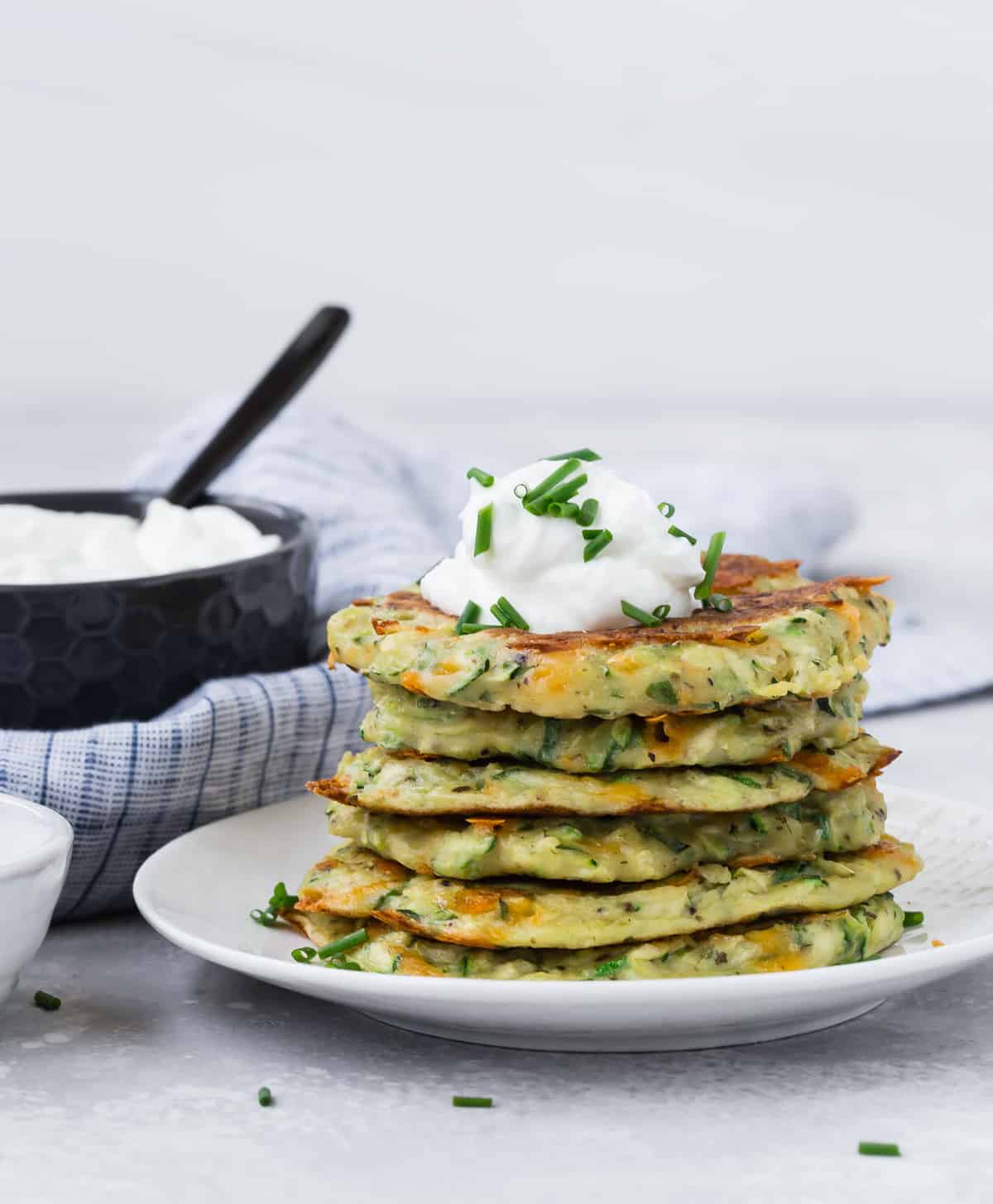 zucchini pancakes stacked on a white plate.