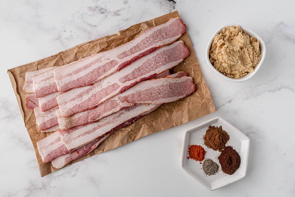 Overhead view of ingredients:: raw bacon, spices, brown sugar.