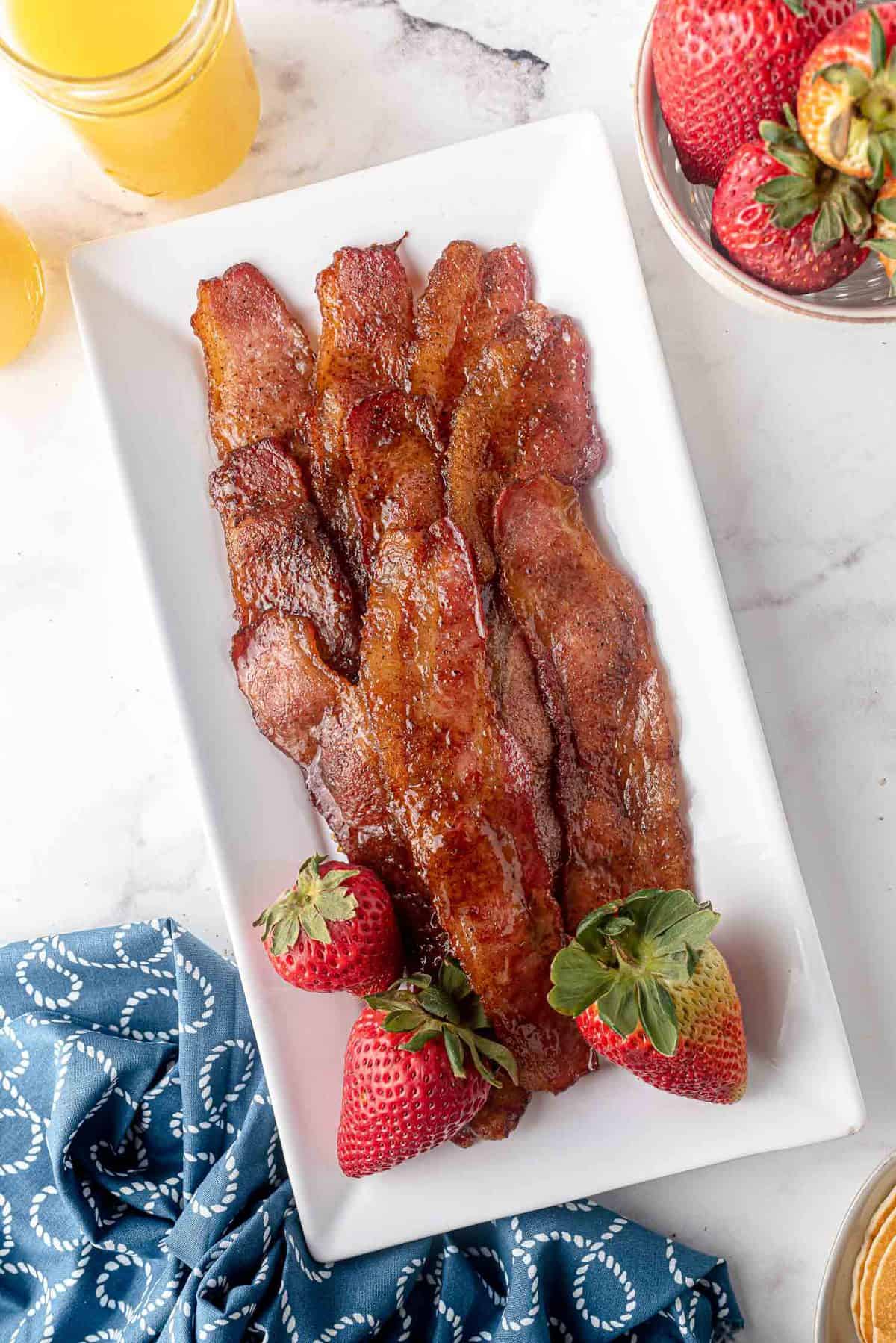 Candied bacon on a rectangular white plate.
