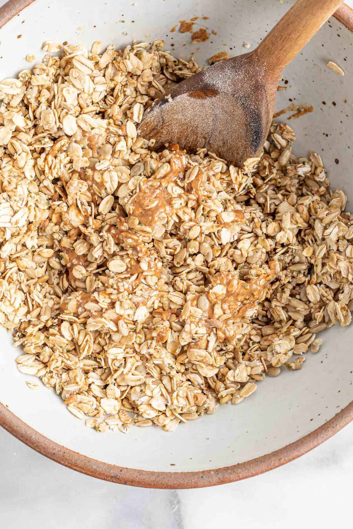 Oatmeal mixture being combined with a wooden spoon.