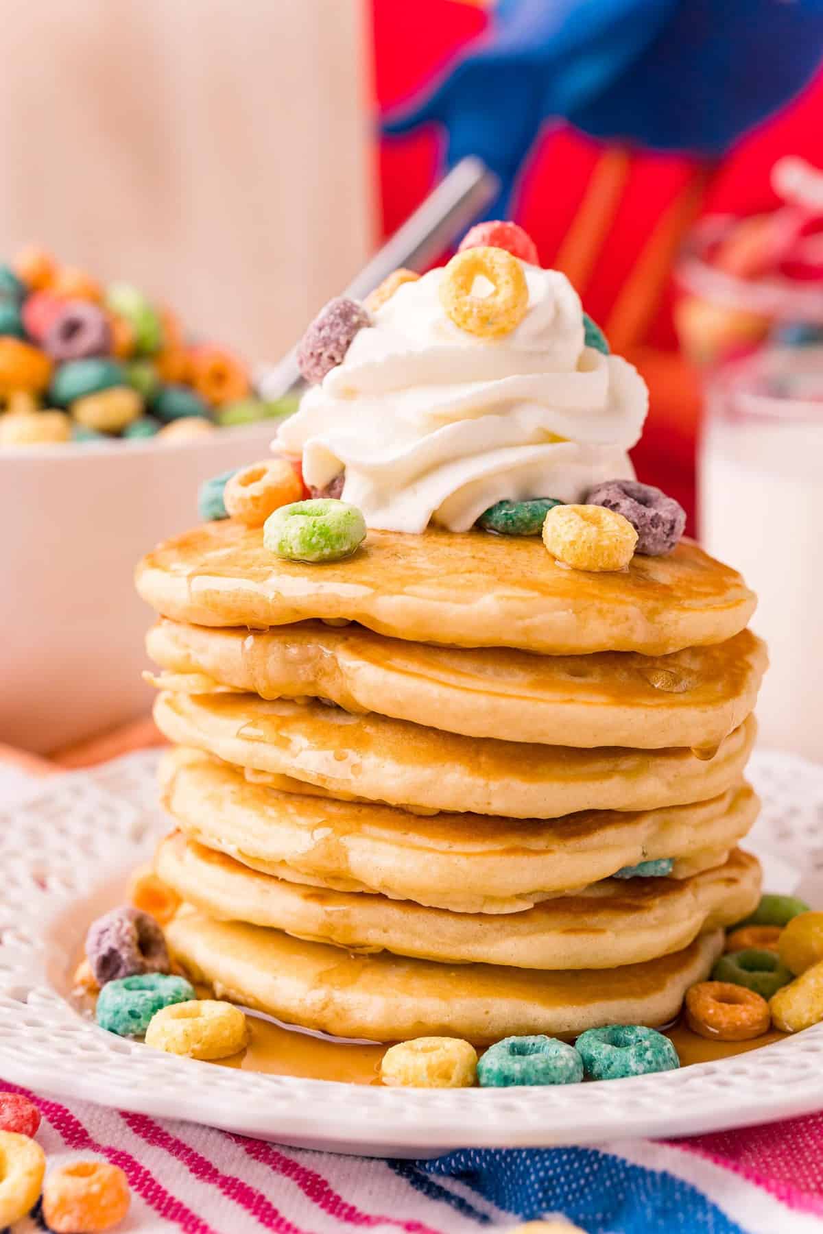 Pancakes topped with Froot Loops cereal, whipped cream, and syrup.