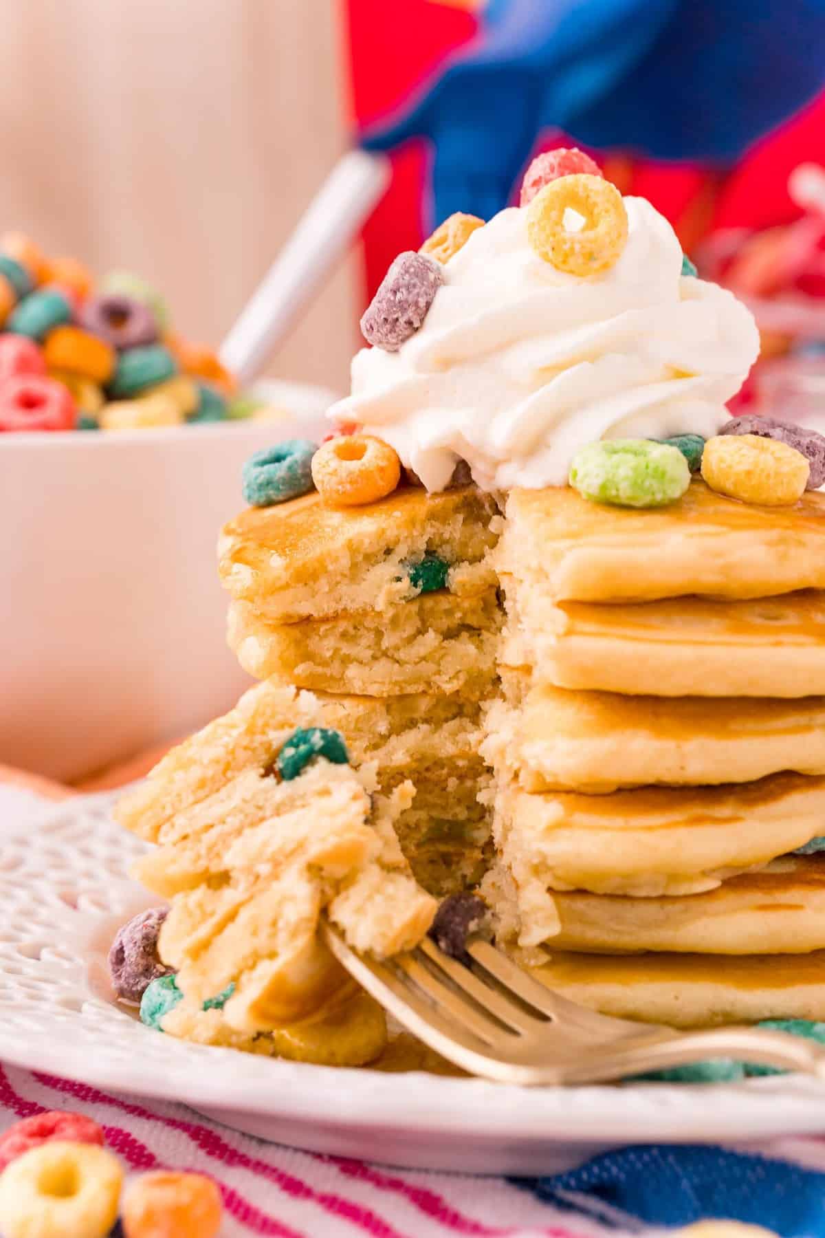 Froot loop pancakes in a large stack, a wedge cut out to show texture.