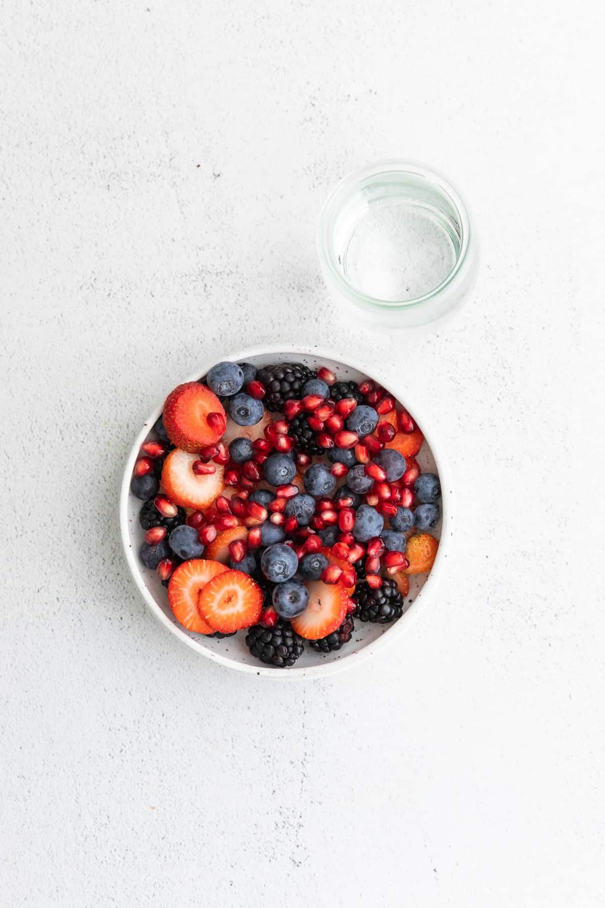 Fruit in a bowl with a glass of coconut water next to it.