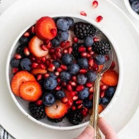 Fruit in a bowl with coconut water and a spoon.