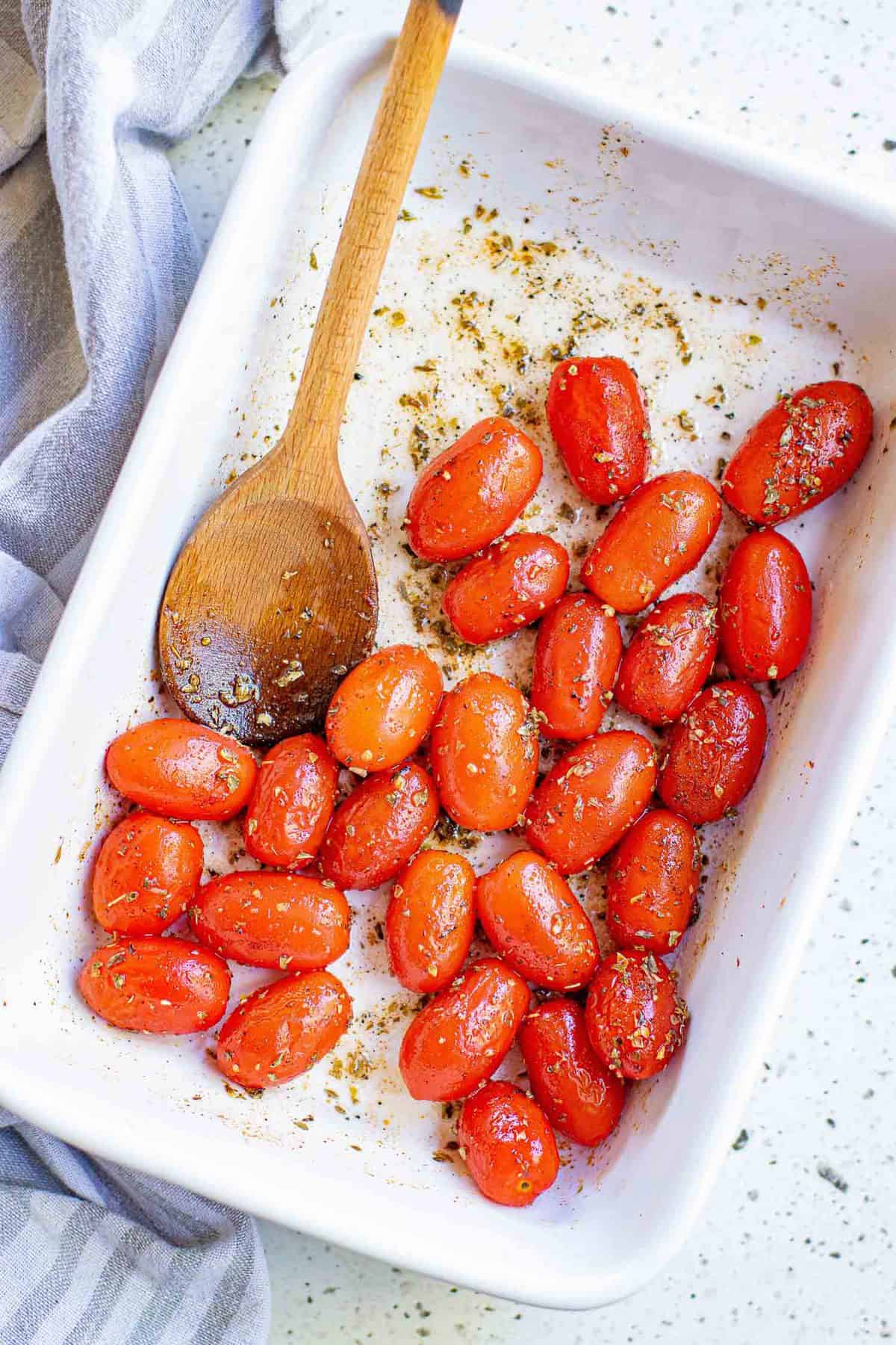 Tomatoes and seasonings in a white baking dish.