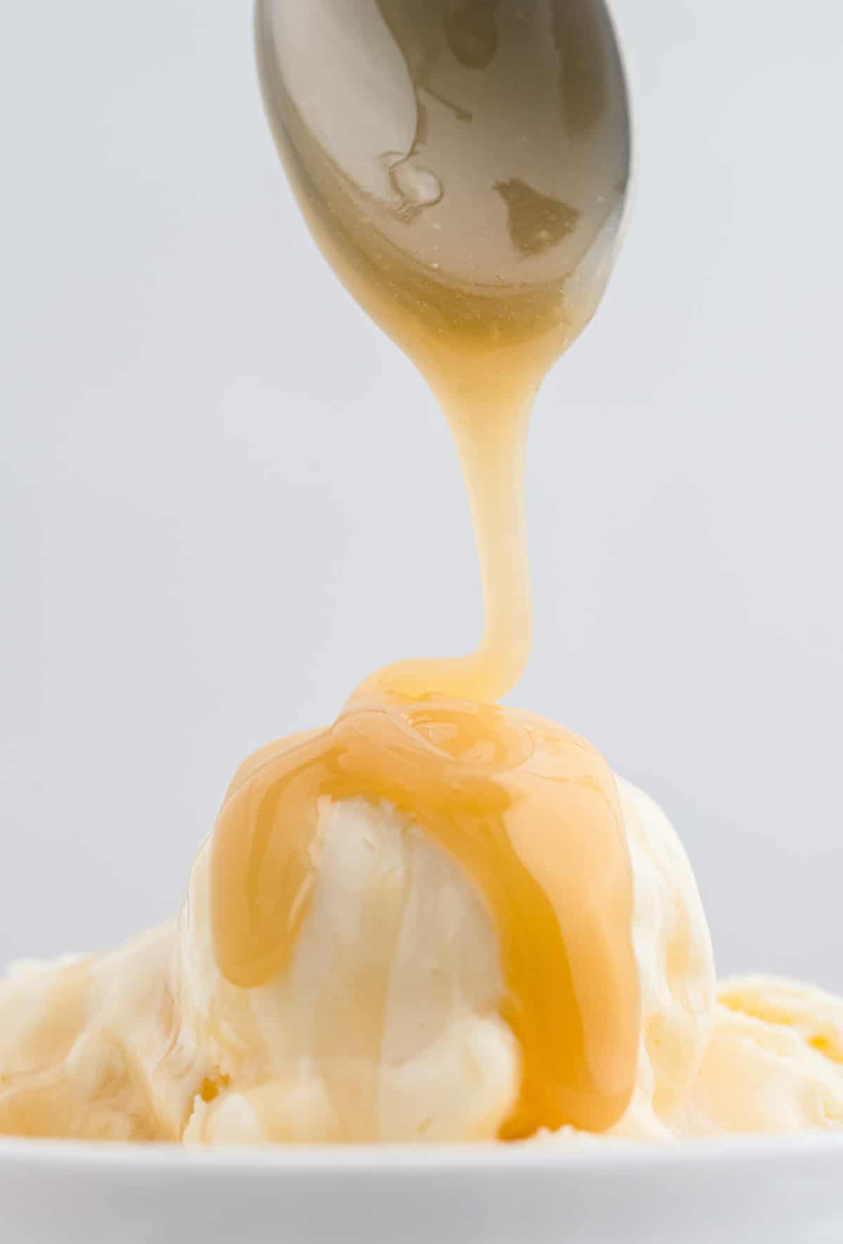 Caramel being drizzled on vanilla ice cream.