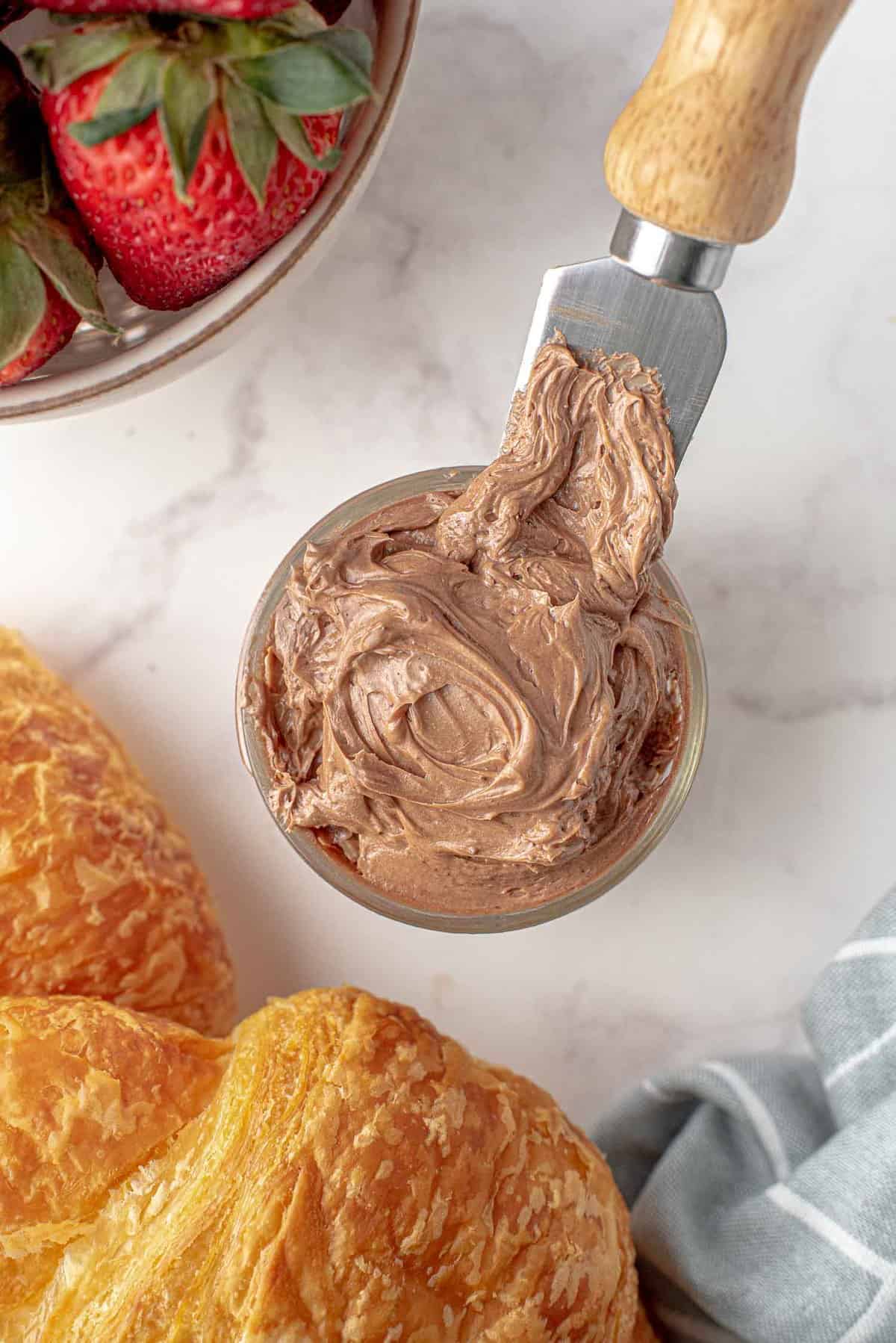 Chocolate butter in a small jar, croissants nearby.