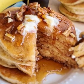 Pancakes topped with butter, walnuts, and syrup.