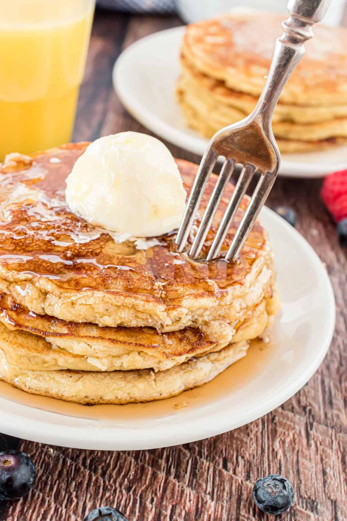 Stack of pancakes with a fork in them.