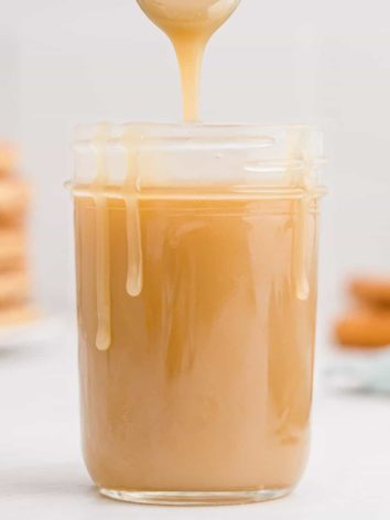 Caramel in a jar and dripping down sides of jar and off spoon.