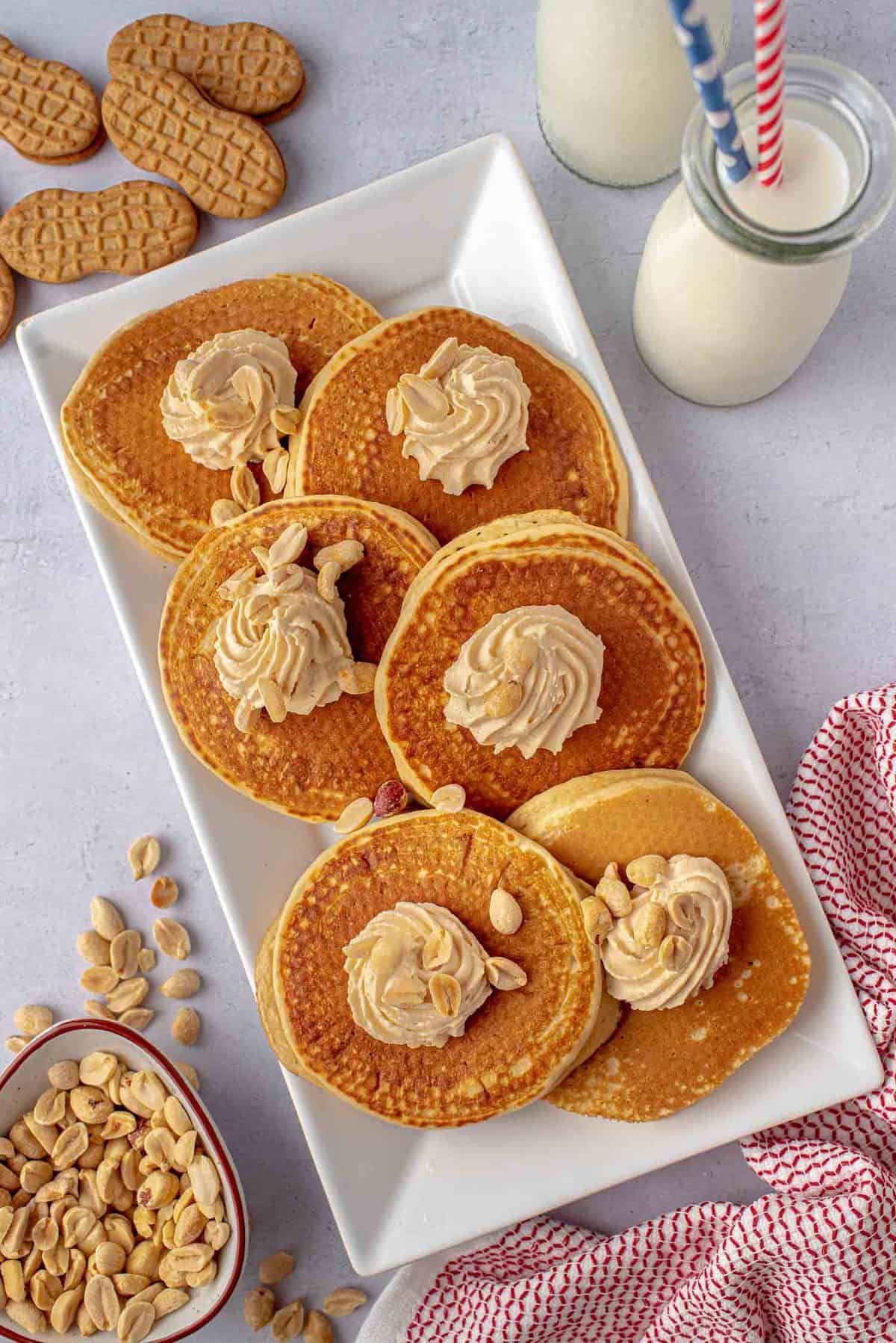 Pancakes on a rectangular platter with peanut butter whipped cream.