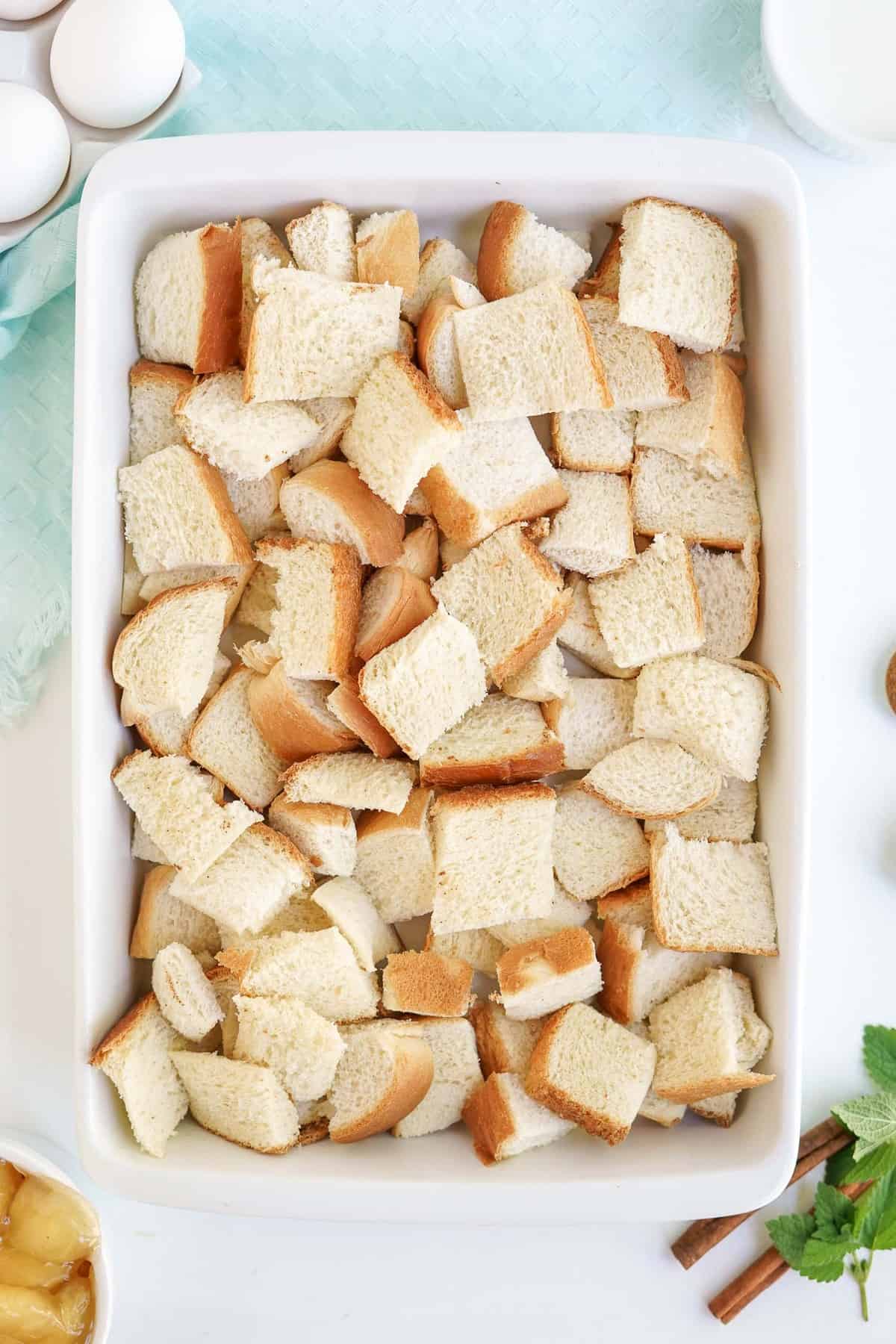 Cubed bread in a white baking dish.