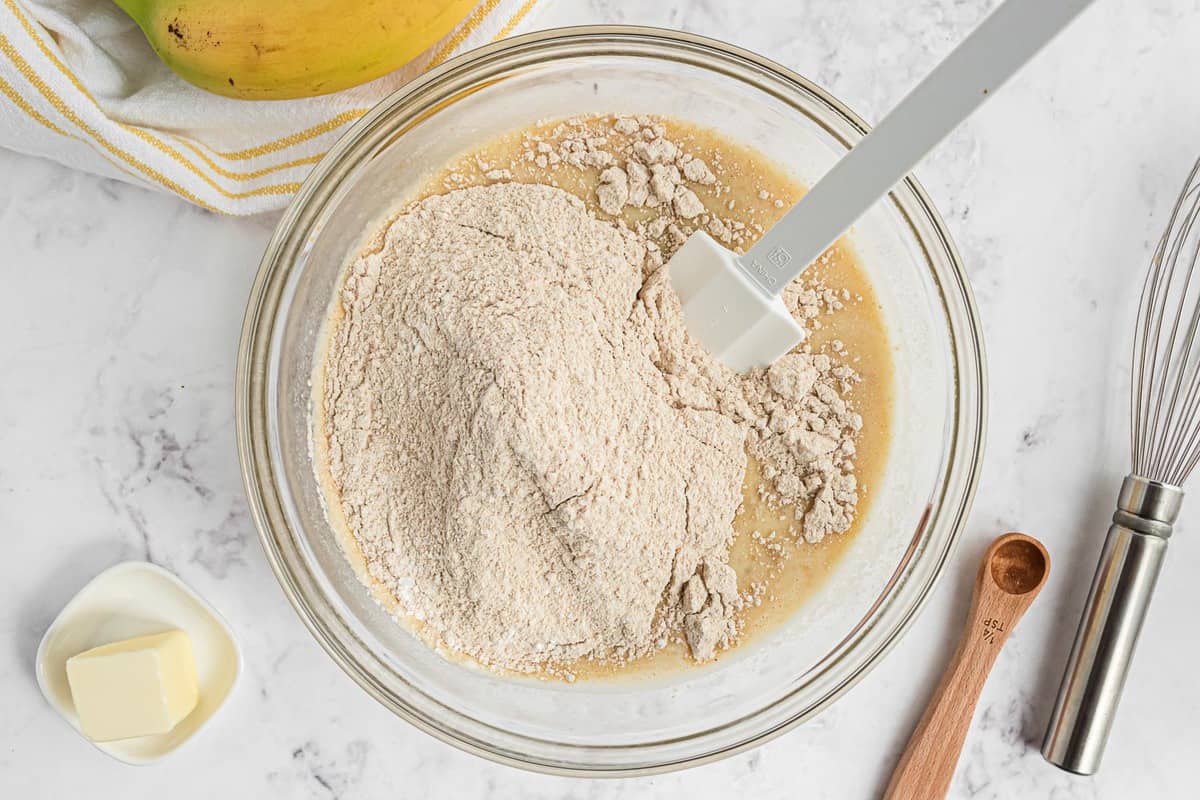 Dry ingredients on top of wet ingredients in a glass bowl.
