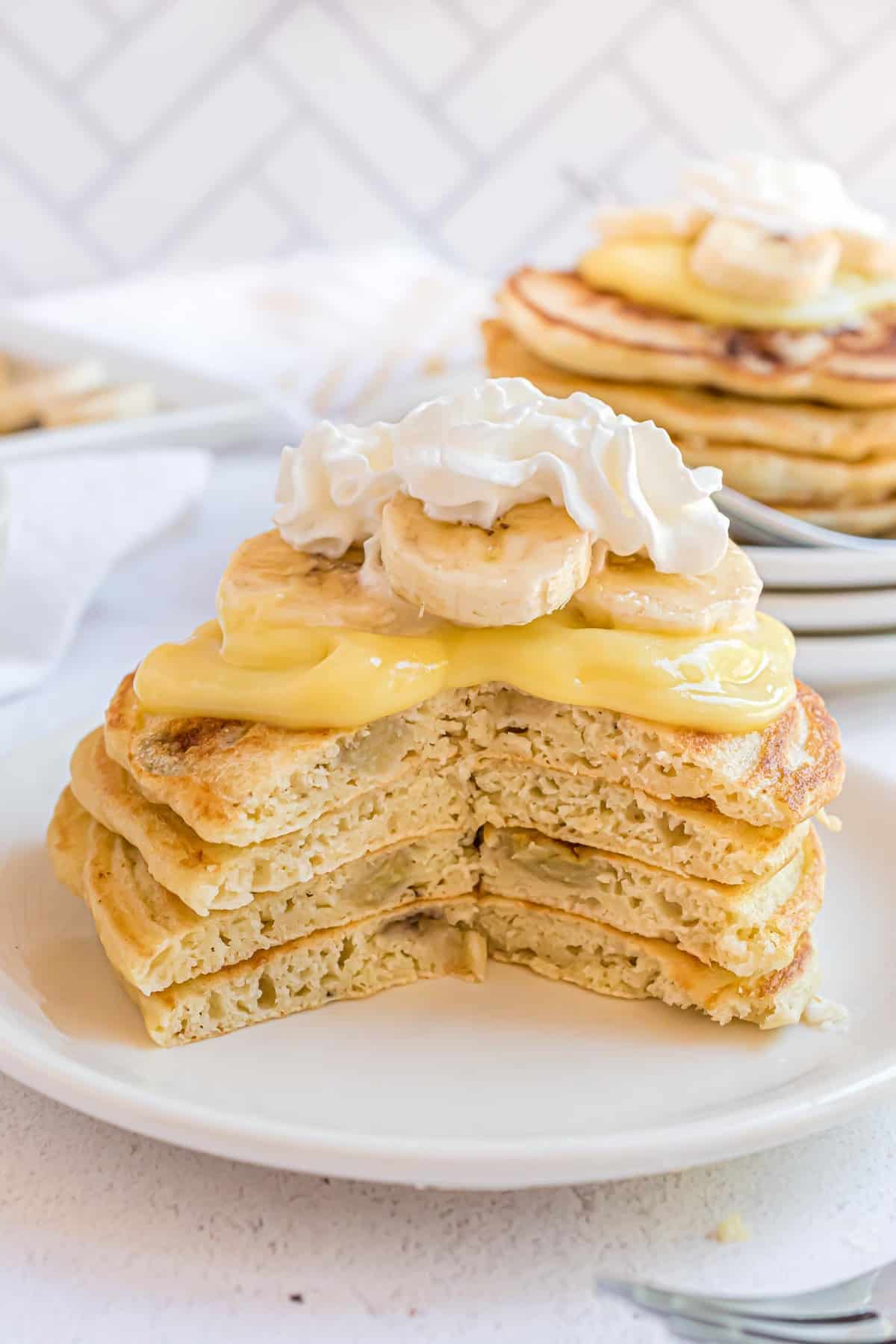 Stack of pancakes with a cut out of it to show bananas in pancakes.
