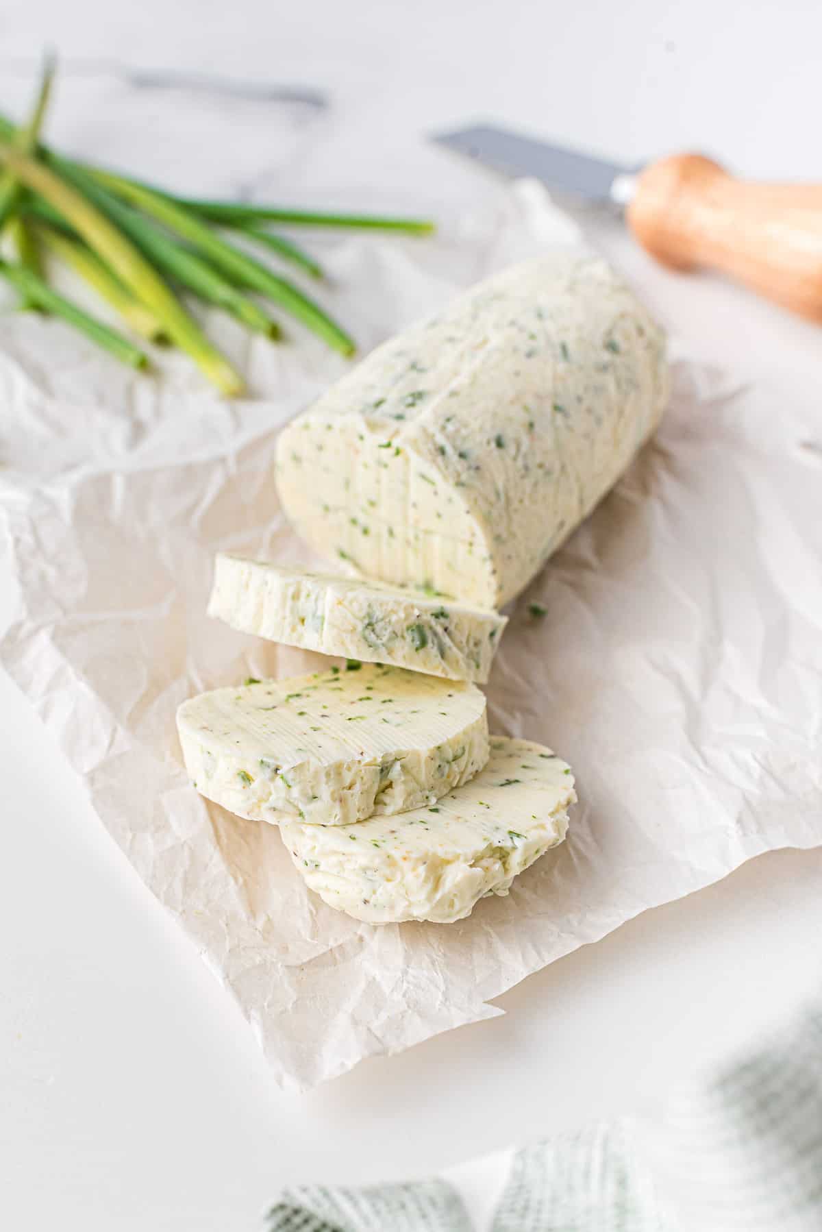 Large log of chive butter, with three slices cut off.