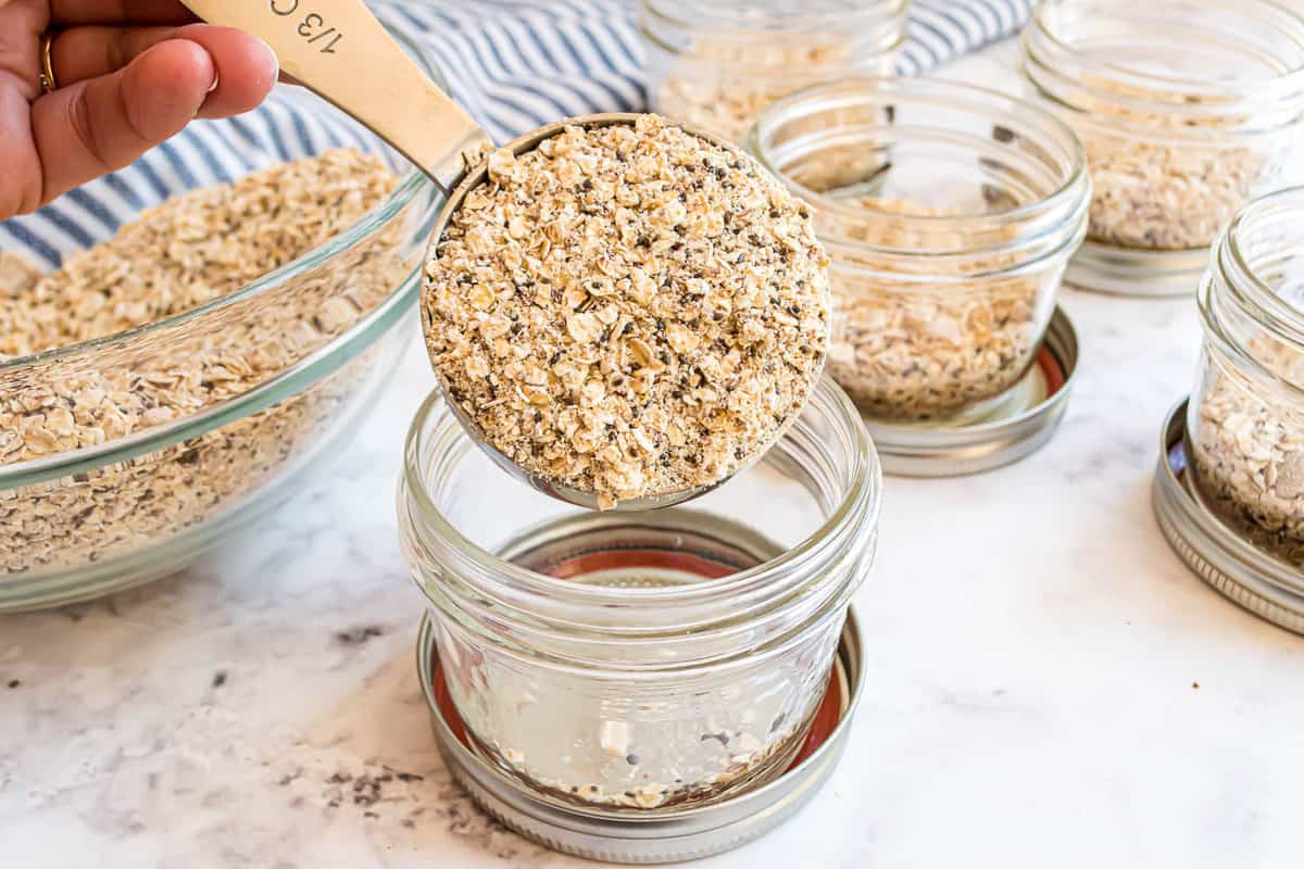 Oatmeal being scooped into small glass jars.