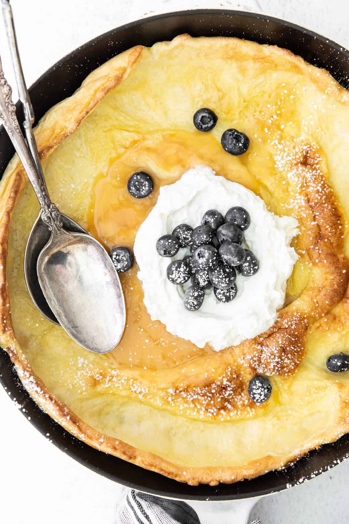 Close up of a dutch baby topped with lemon curd and blueberries.
