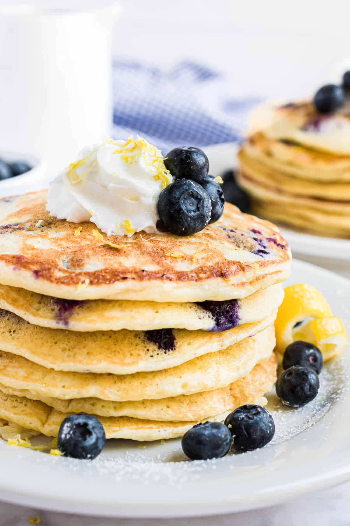 Stack of pancakes topped with fresh blueberries and whipped cream.