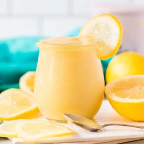 Lemon curd in a small jar garnished with a lemon wheel.