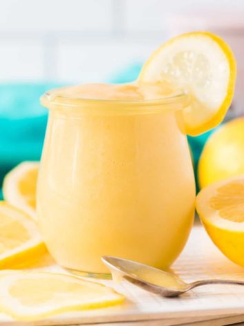 Lemon curd in a small jar garnished with a lemon wheel.