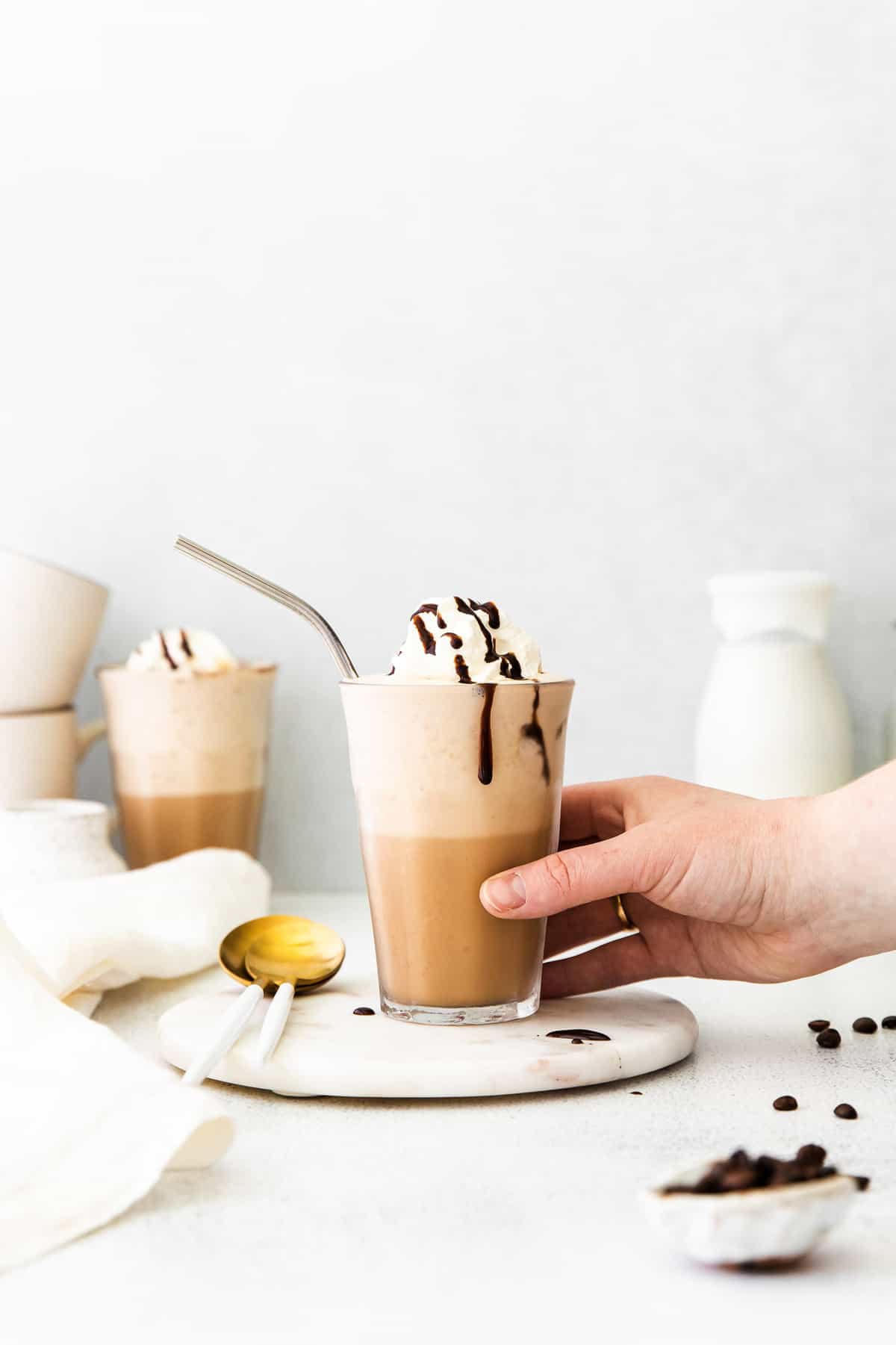 Hand grabbing a whipped cream topped coffee drink.