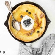Overhead view of dutch baby pancake topped with blueberries and whipped cream.