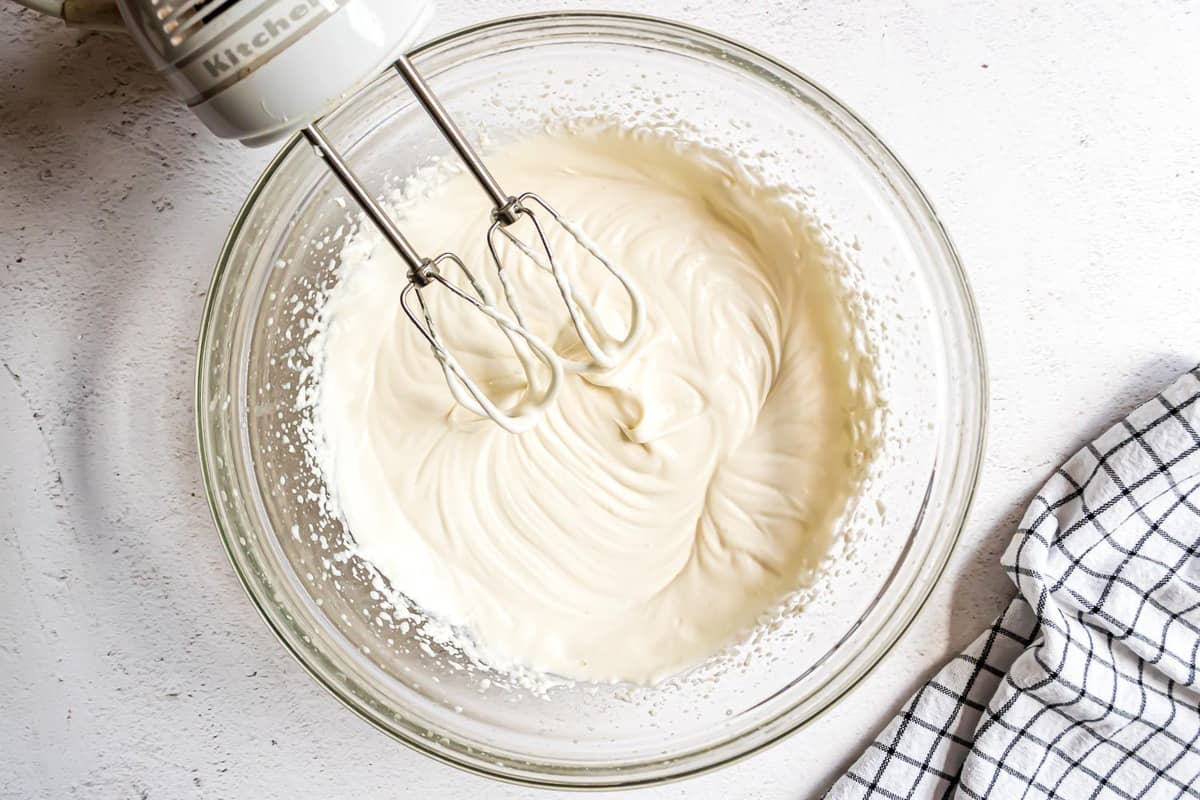 Mascarpone filling in a clear glass mixing bowl with electric mixer.