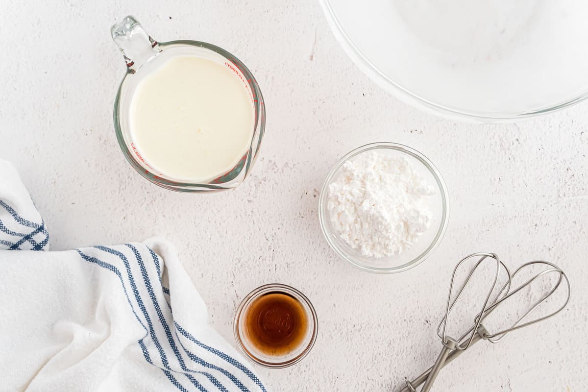 Overhead view of vanilla, powdered sugar, and heavy cream.