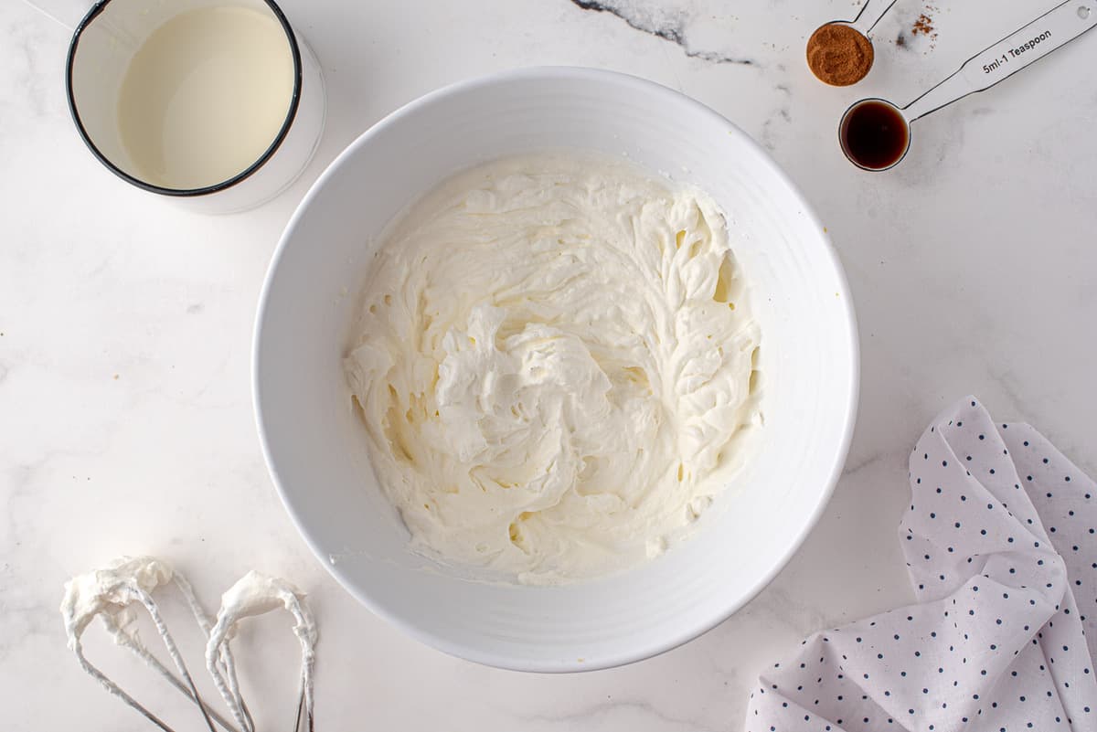 Whipped ream in a white mixing bowl.