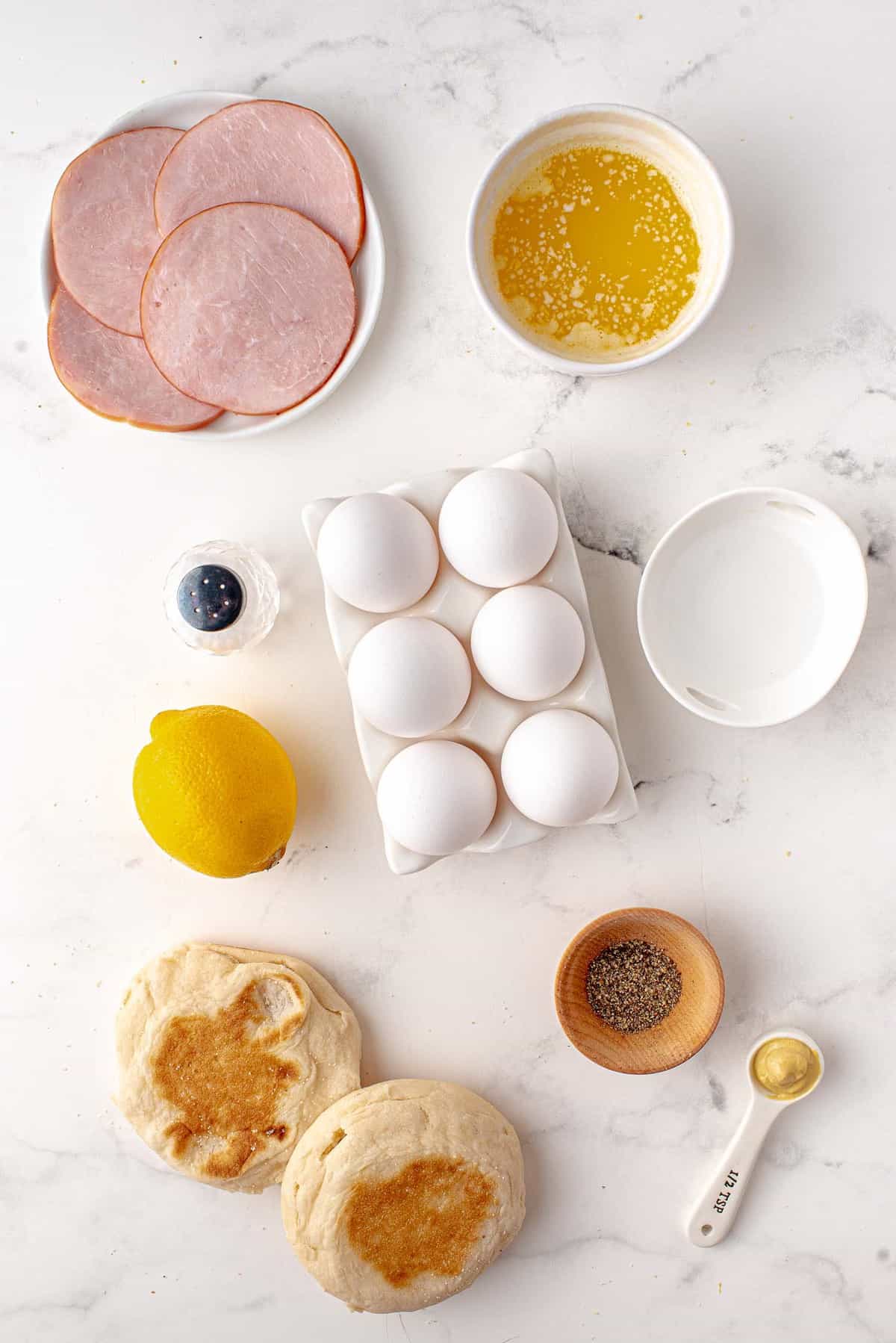 Overhead view of ingredients including eggs and english muffins.