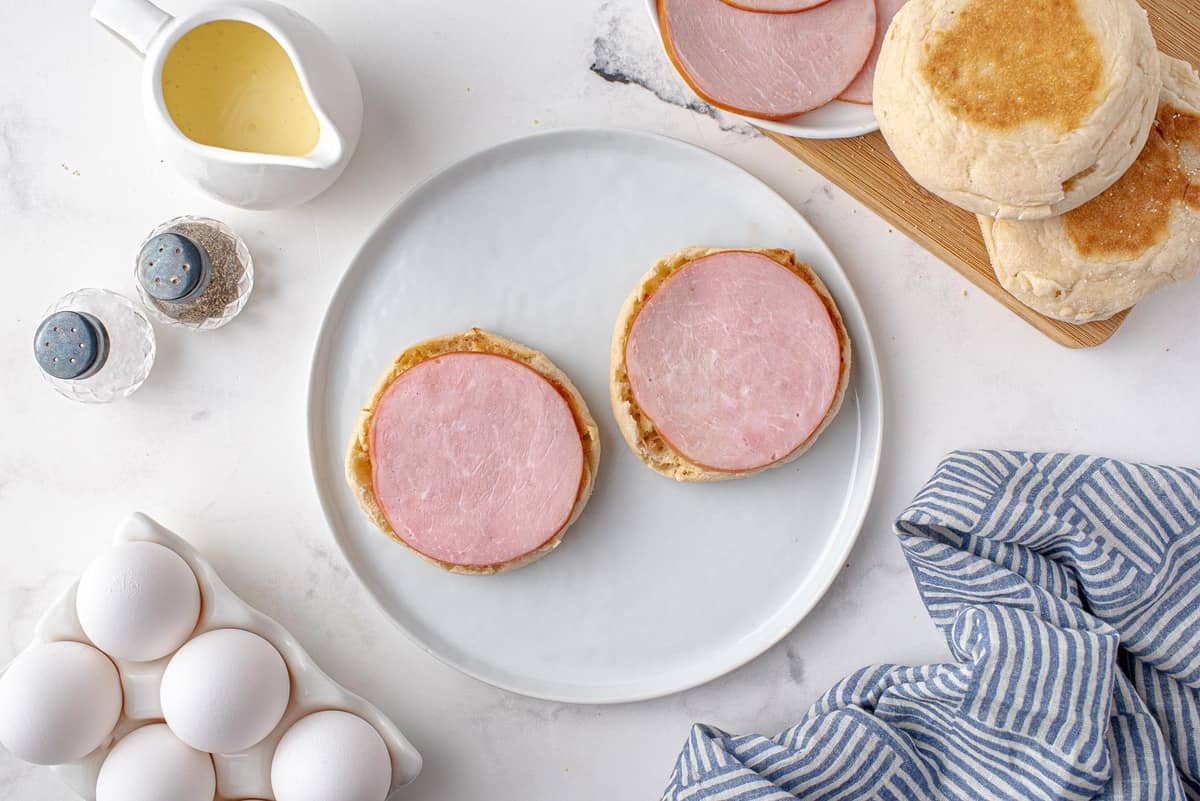 English muffin with canadian bacon on a white plate.