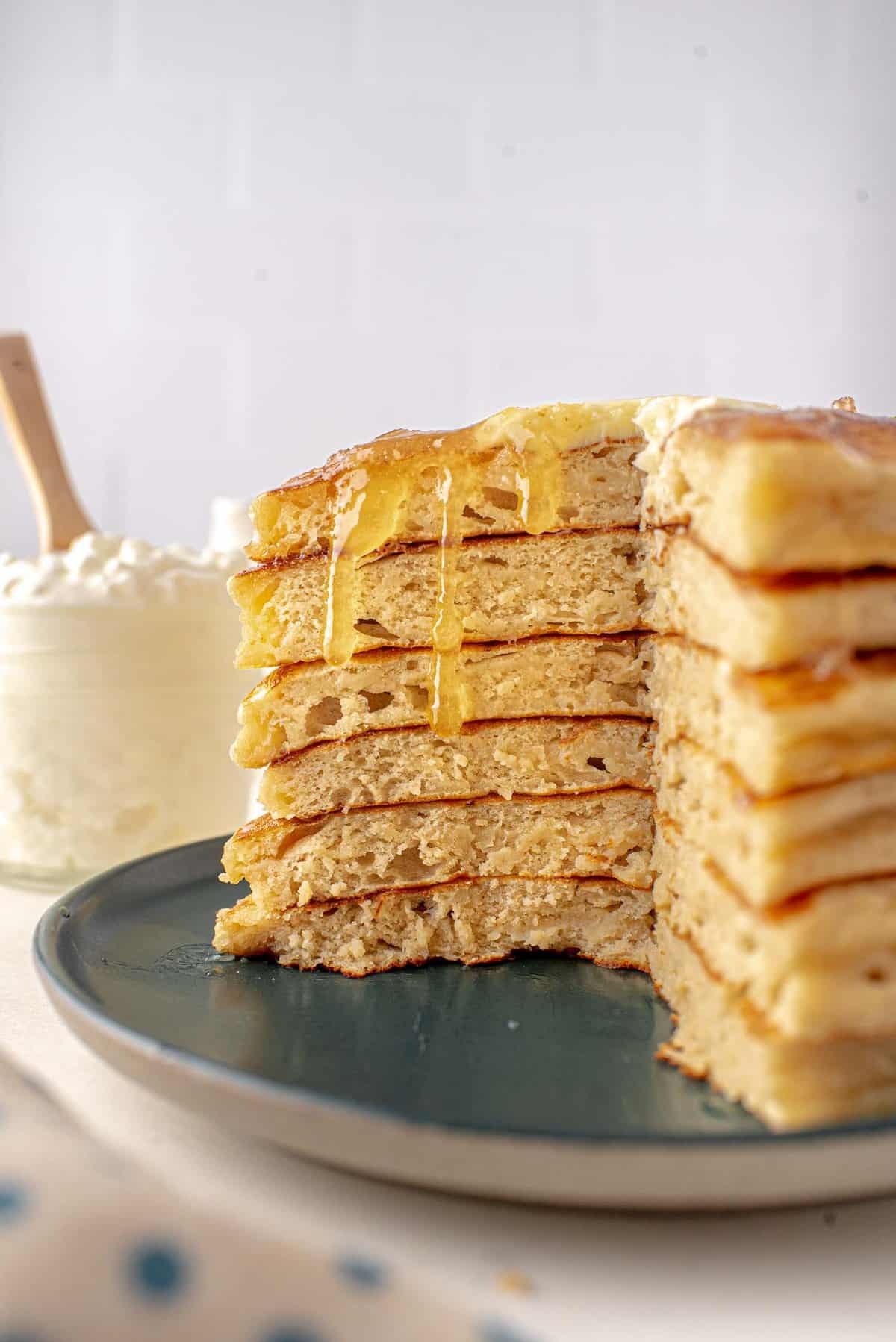 Stack of pancakes, cut to show texture, syrup dripping down cut edge.